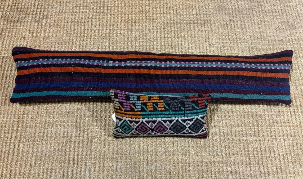 A striped pillow and a smaller pillow are sitting on a table.