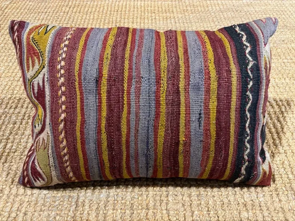 A colorful striped pillow is sitting on a rug.
