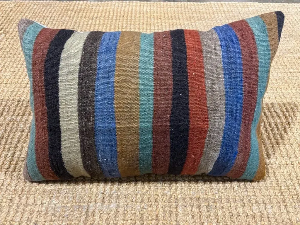 A colorful striped pillow is sitting on a rug.