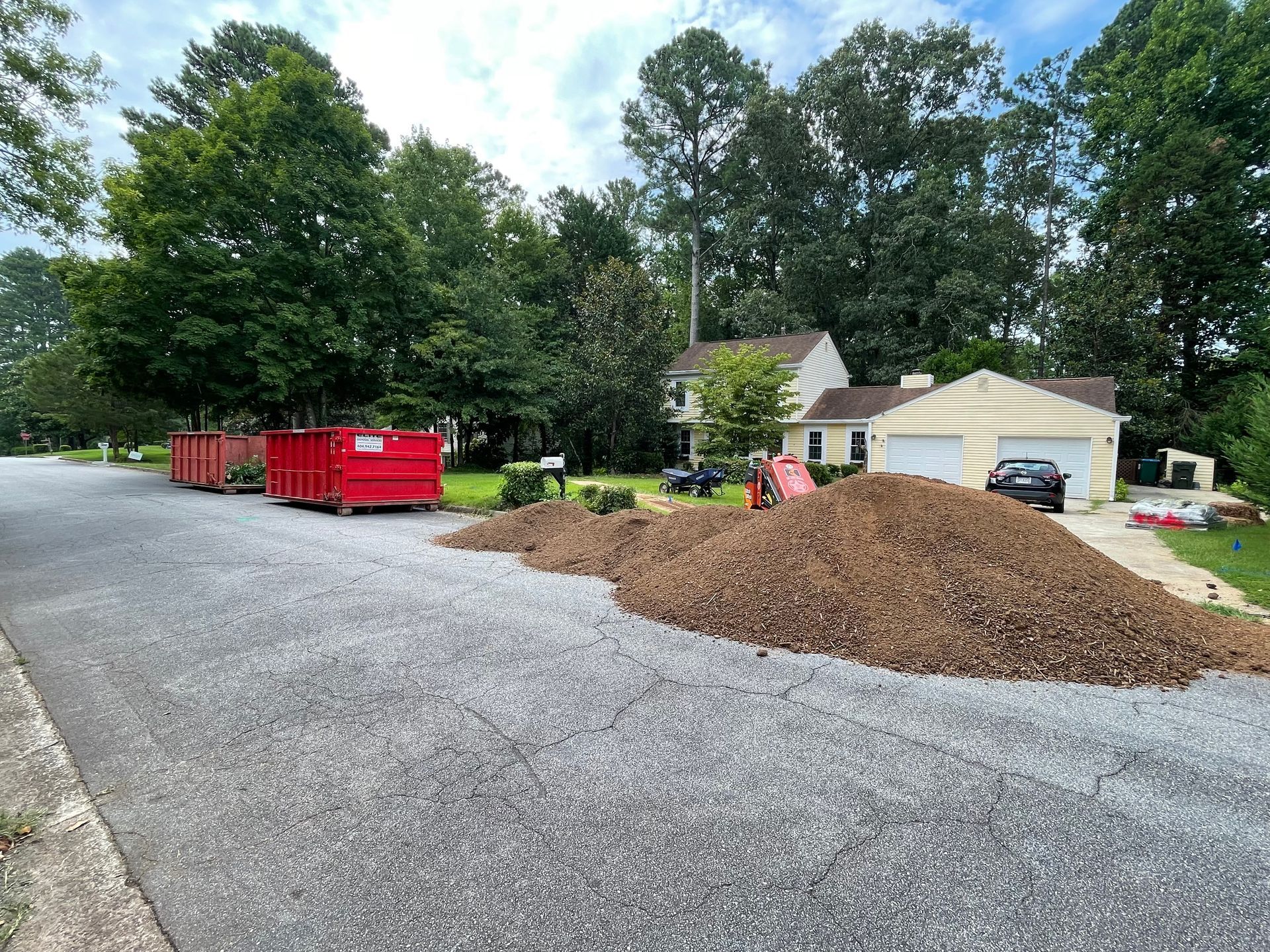 A pile of mulch is sitting on the side of a road next to a house.