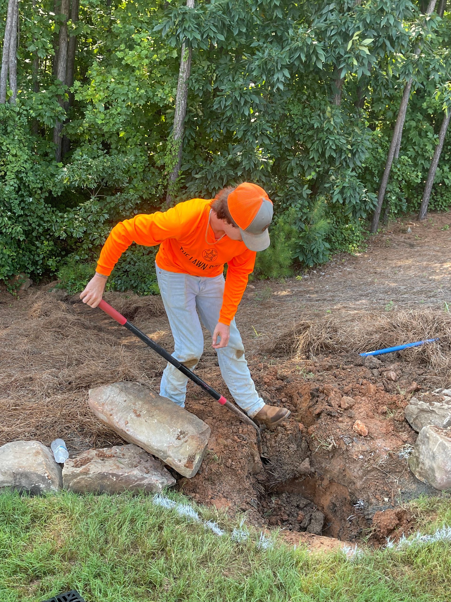 A man is digging a hole in the ground with a shovel.