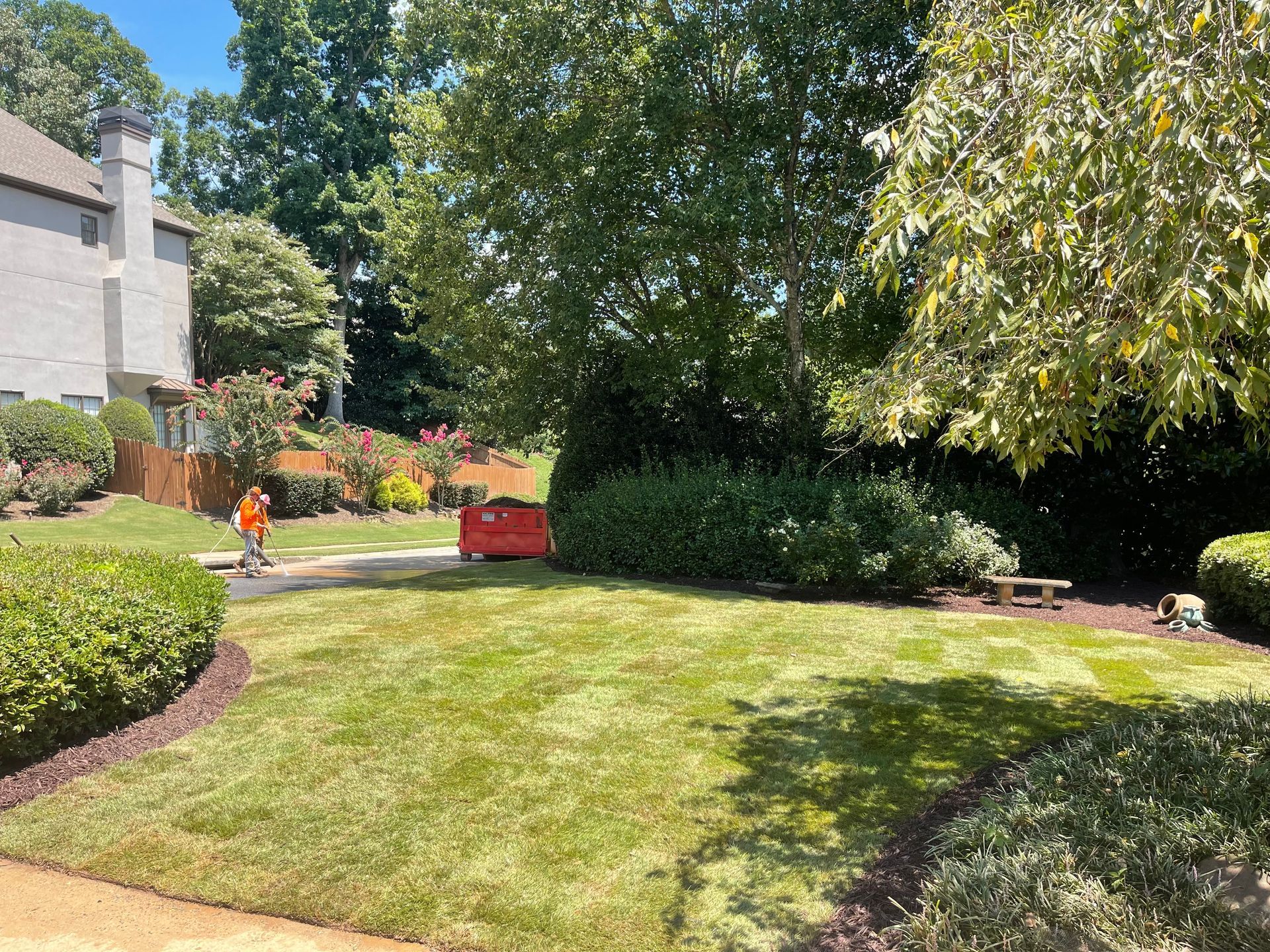 A man is mowing a lush green lawn in front of a house.