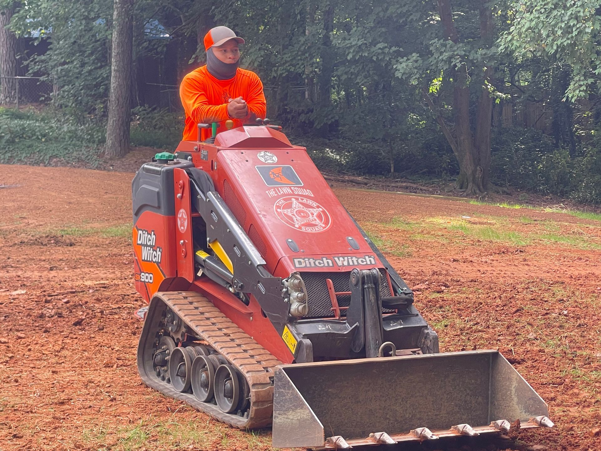 A man in an orange shirt is driving a red tractor