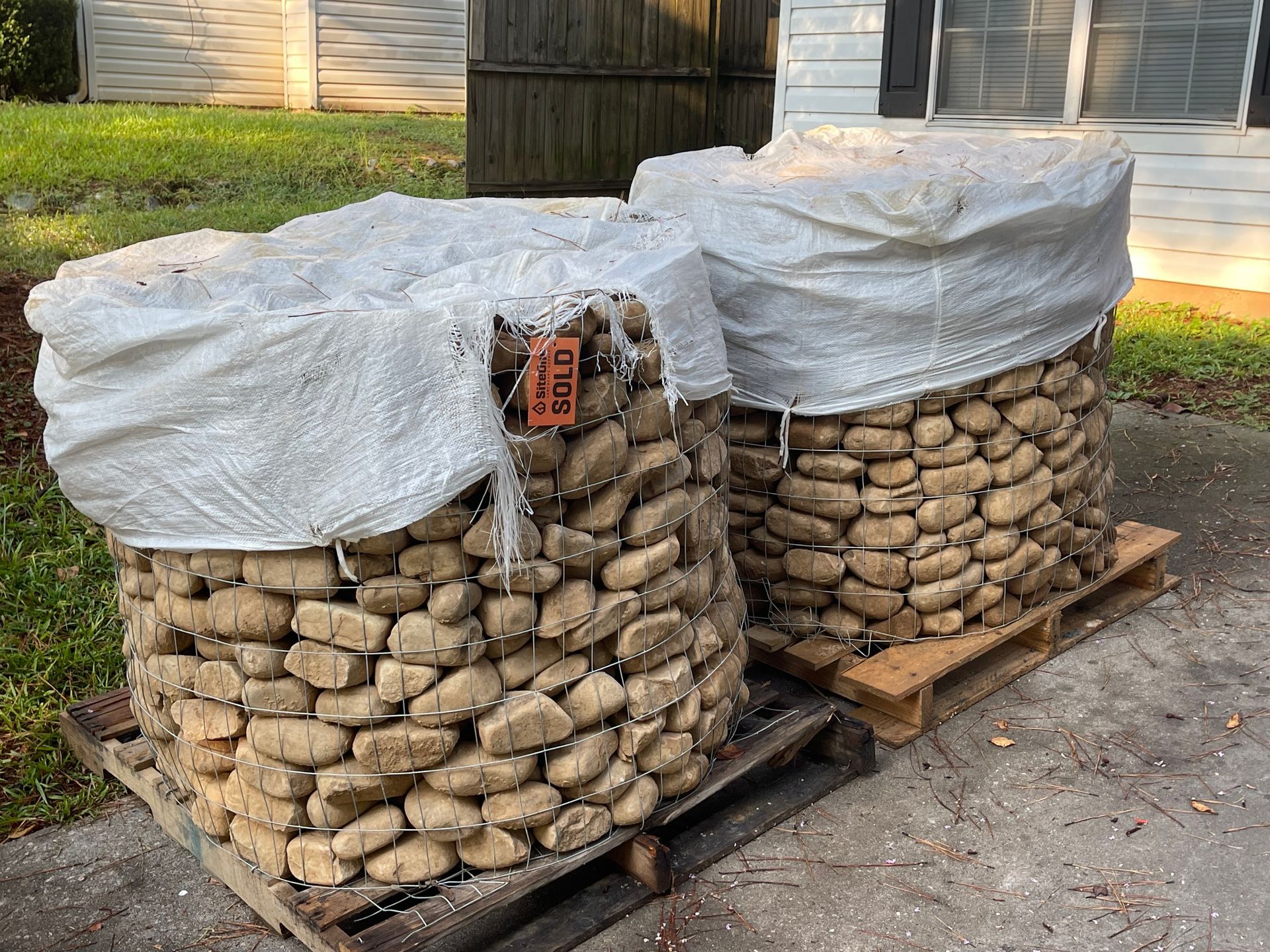 Two bags of rocks are sitting on a wooden pallet.