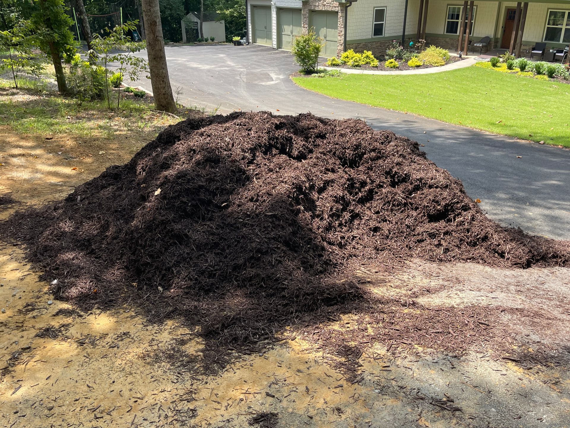 A pile of mulch is sitting on the ground in front of a house.