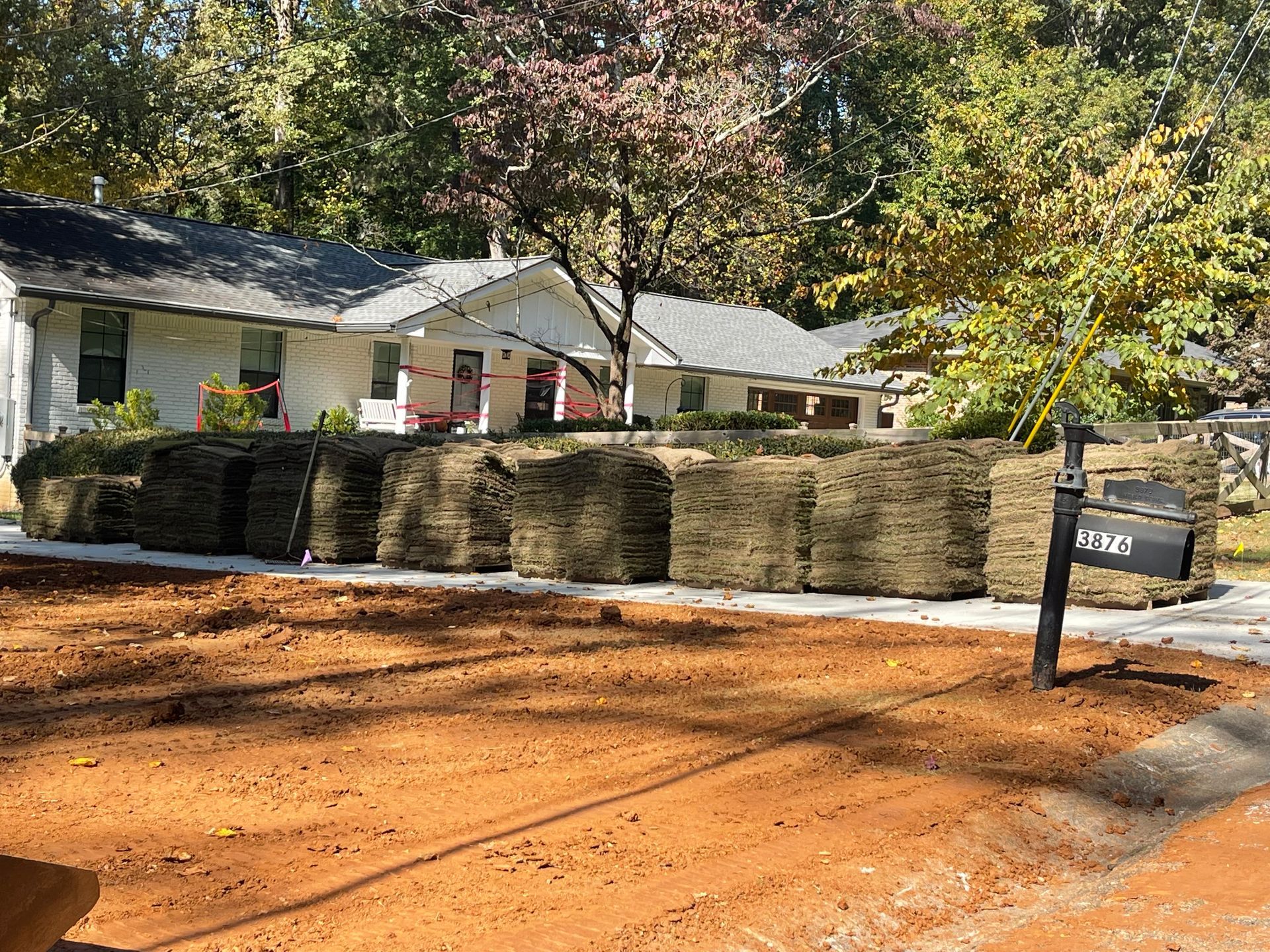 A pile of hay is sitting in front of a house.