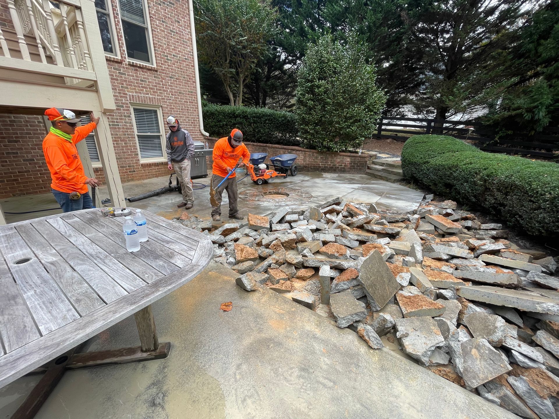 A group of men are working on a patio in front of a house.