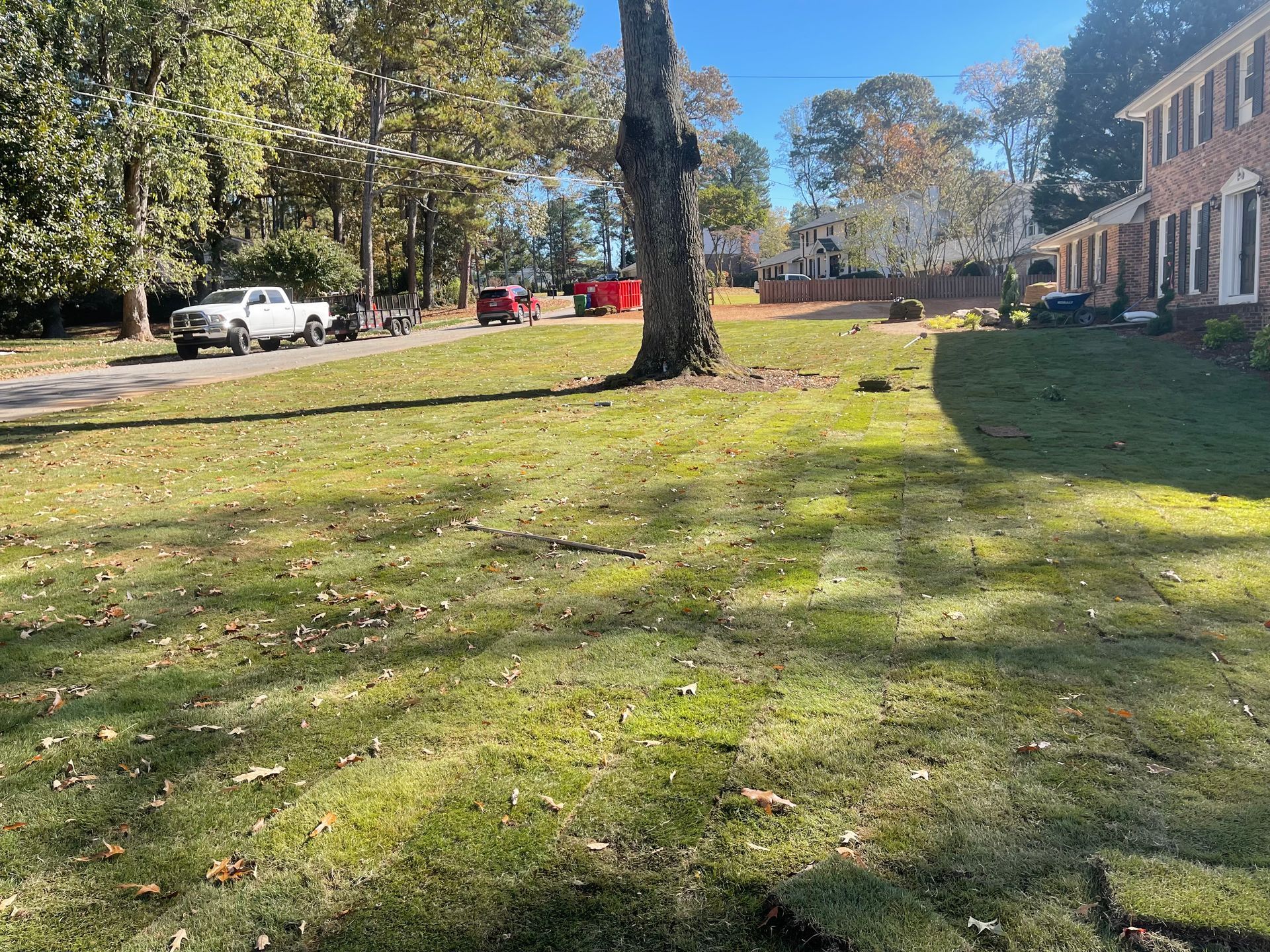 A lush green lawn in front of a house with a truck parked in the driveway.