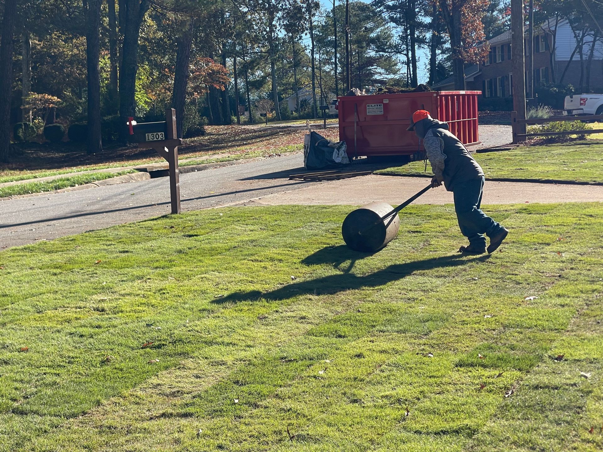 A man is rolling a lawn roller on a lush green field.