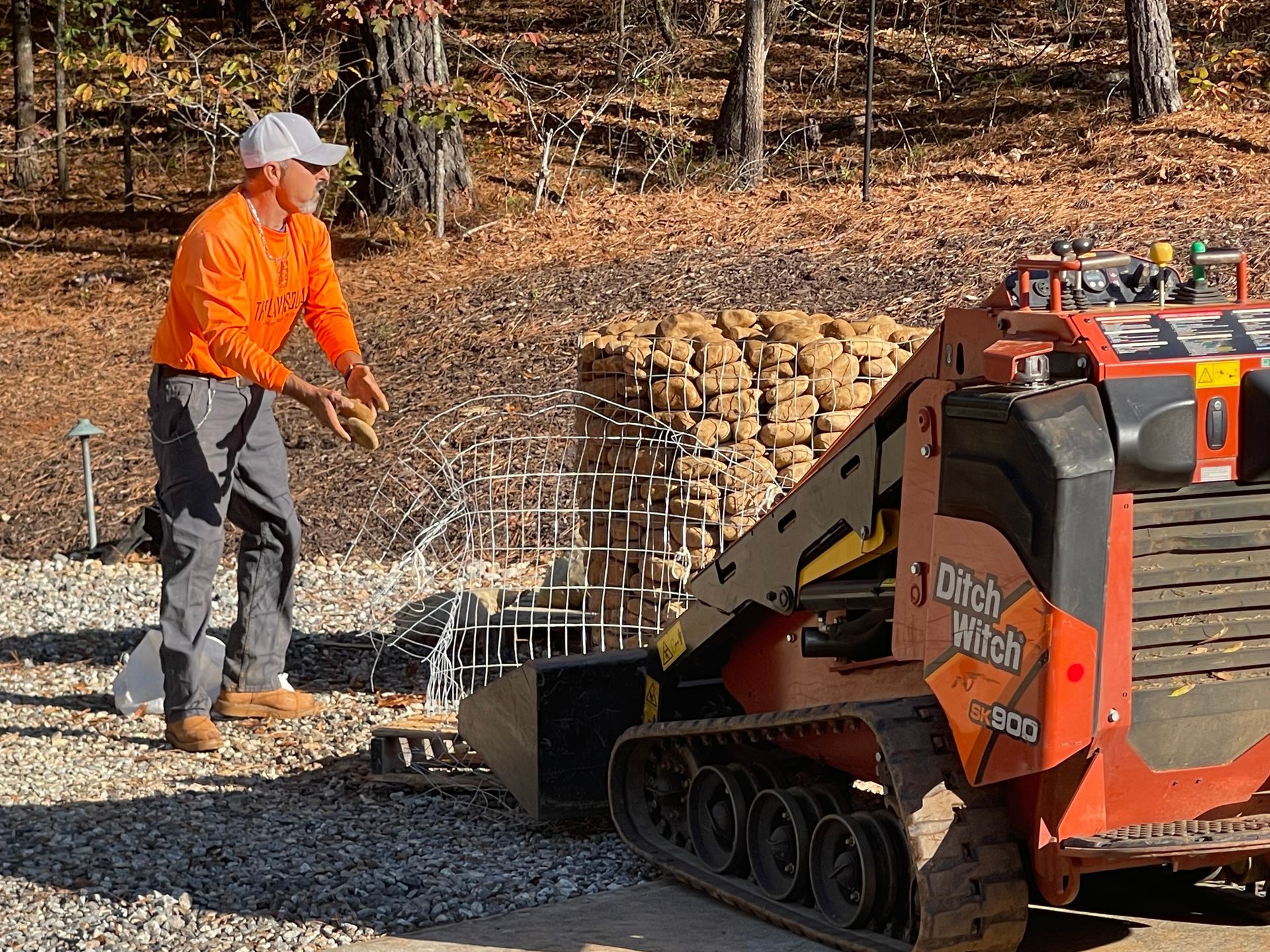 A man in an orange shirt is standing next to a tractor.