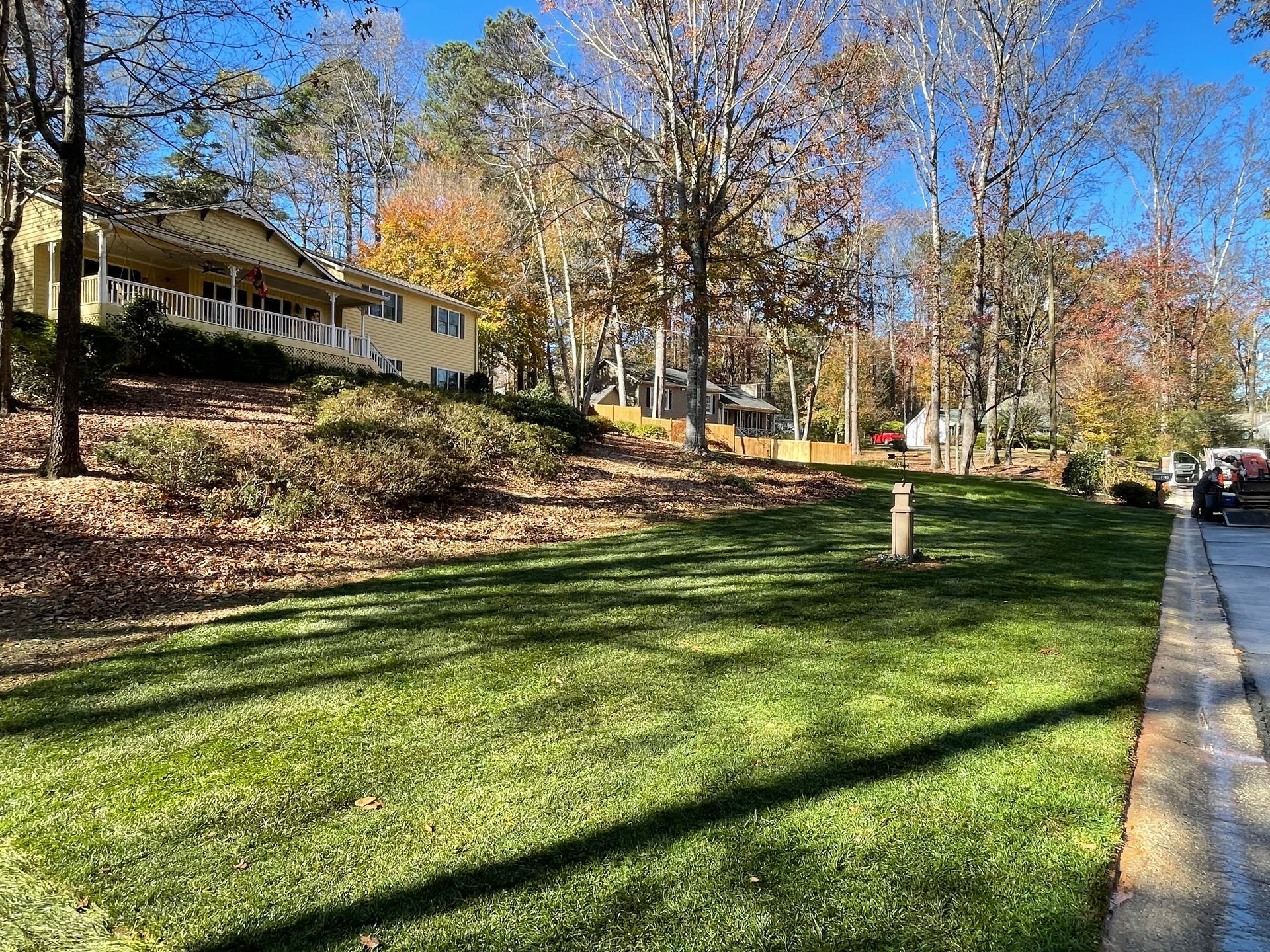 A house is sitting on top of a hill next to a lush green lawn.