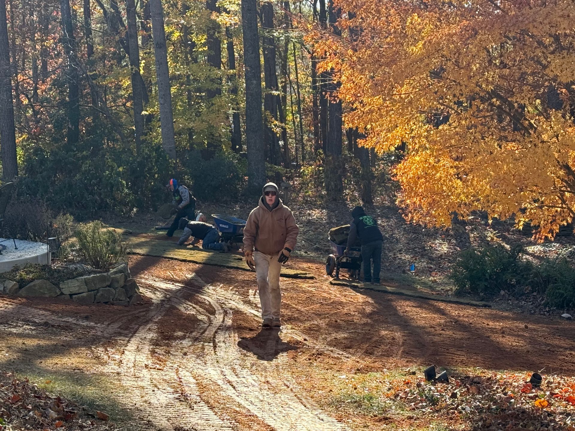 A man is walking down a dirt road in the woods.