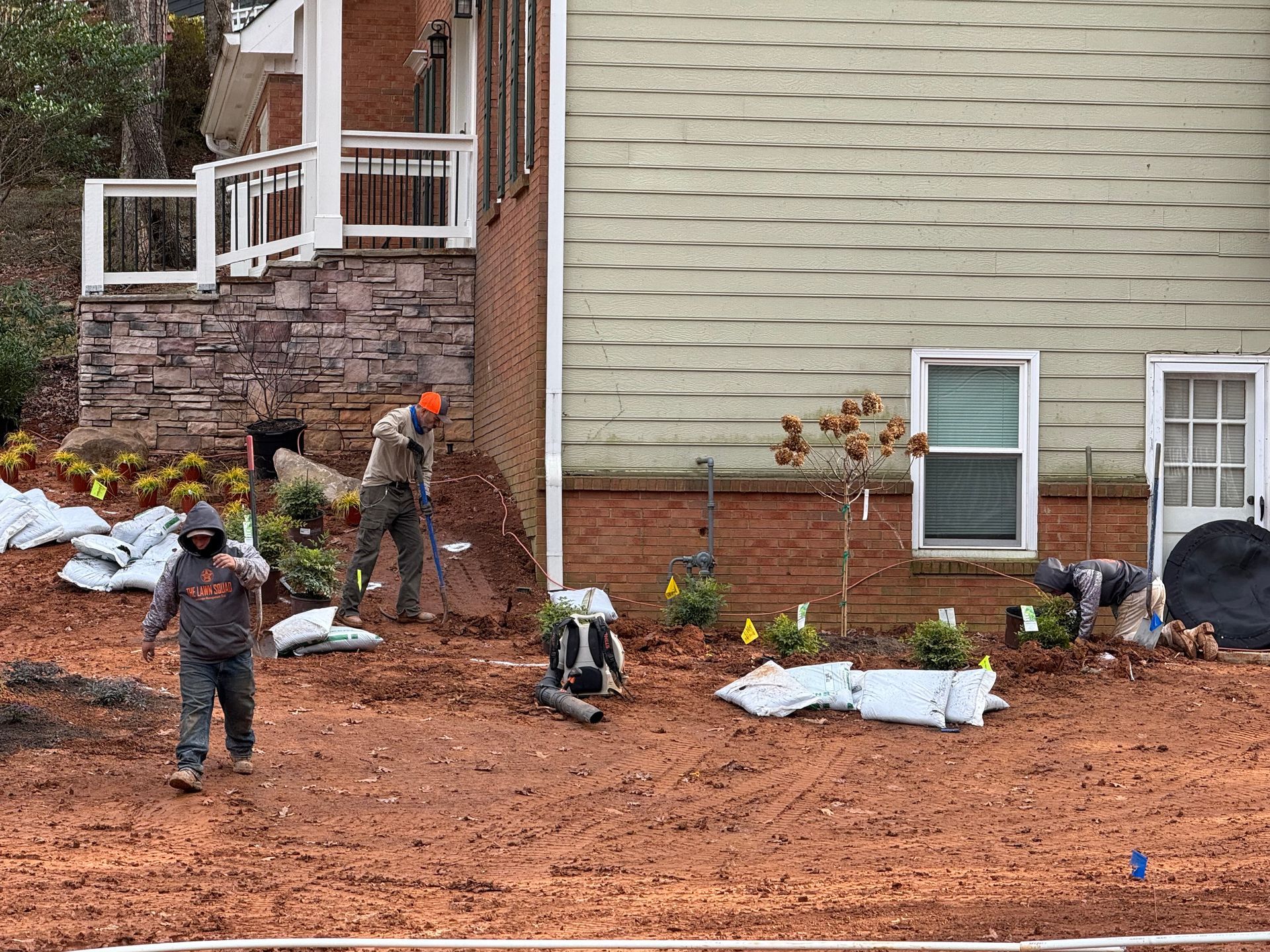 A group of people are working on a lawn in front of a house.