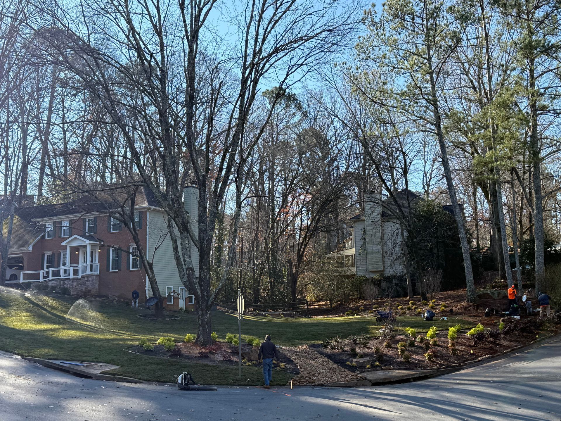 A brick house with a large bay window and a large lawn in front of it.