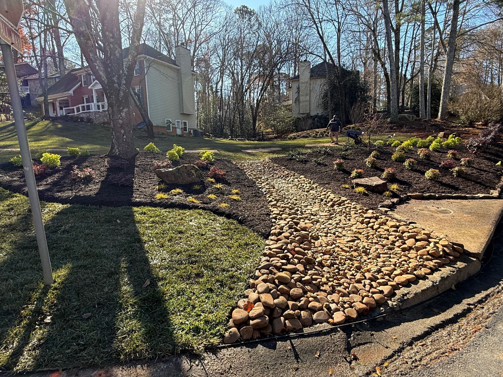 A stone walkway leading to a house with trees in the background.