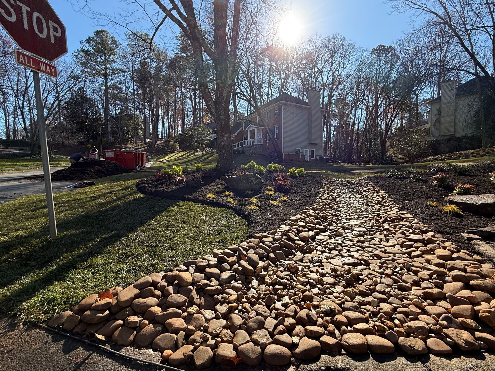 A stop sign is sitting on the side of the road next to a pile of rocks.
