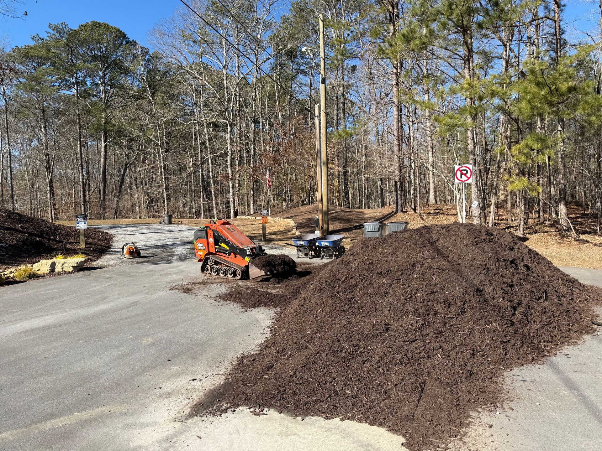 A pile of mulch is sitting on the side of the road next to a tractor.