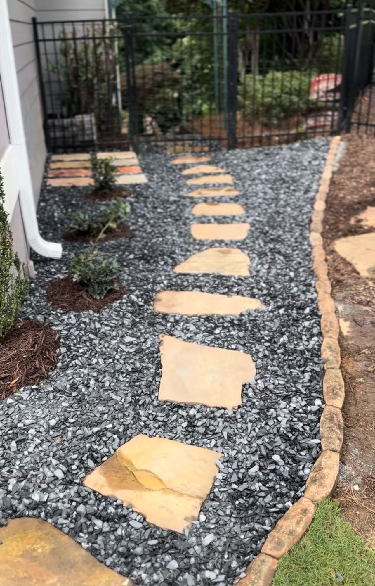 A stone walkway leading to a house with gravel and rocks.