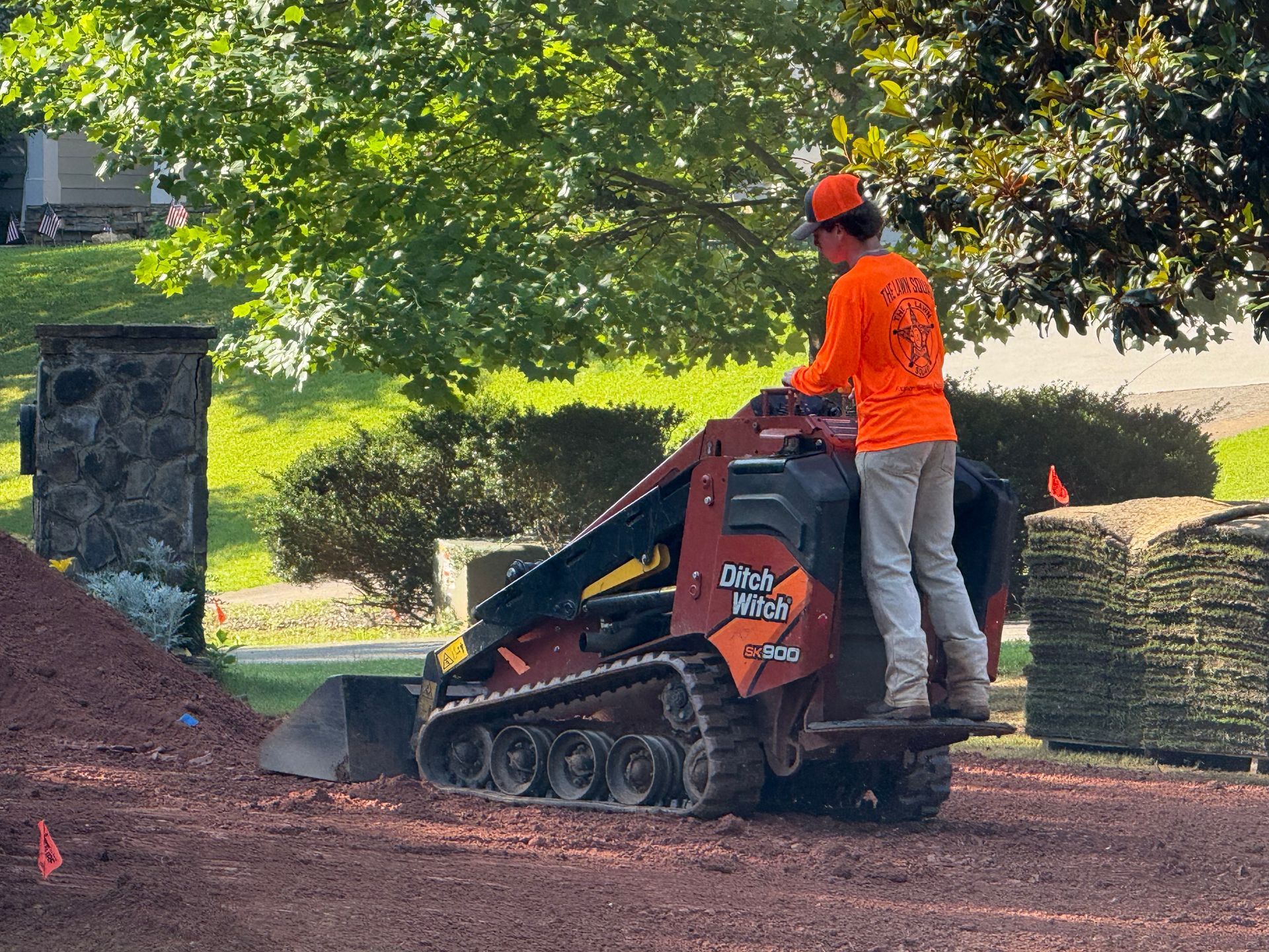 Two bulldozers are sitting on top of a dirt field in front of a house.