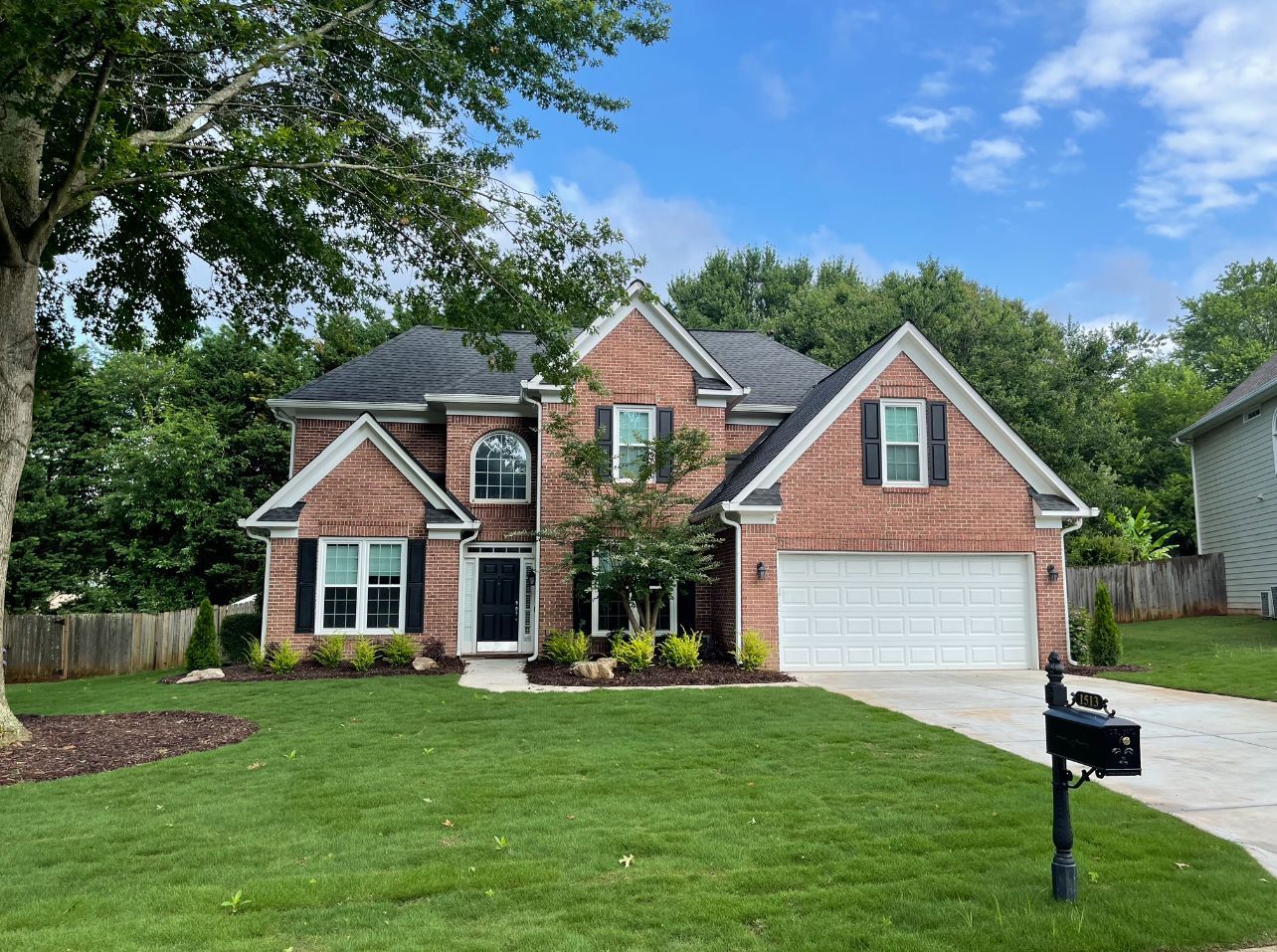 A large brick house with a large driveway and a mailbox in front of it.