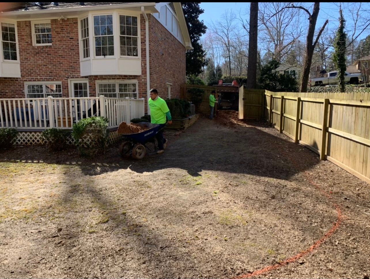 A man is pushing a wheelbarrow full of dirt in front of a house.