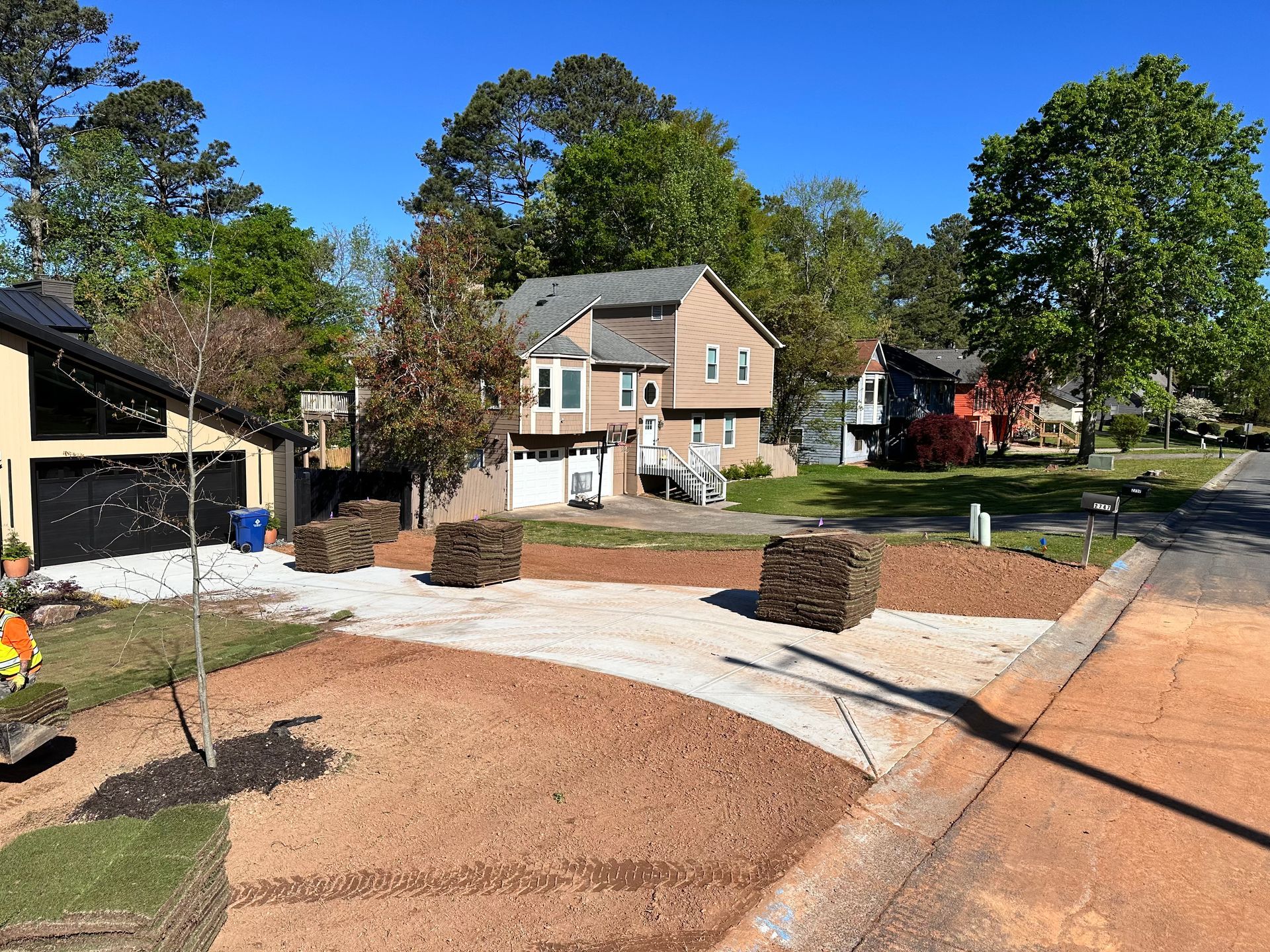 A man is working on a driveway in front of a house.