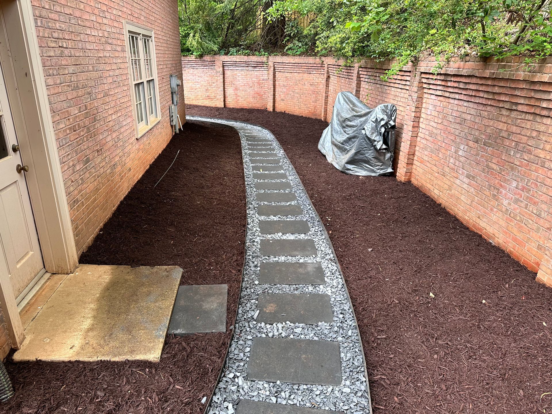 A walkway leading to a house with a motorcycle parked on the side of it.