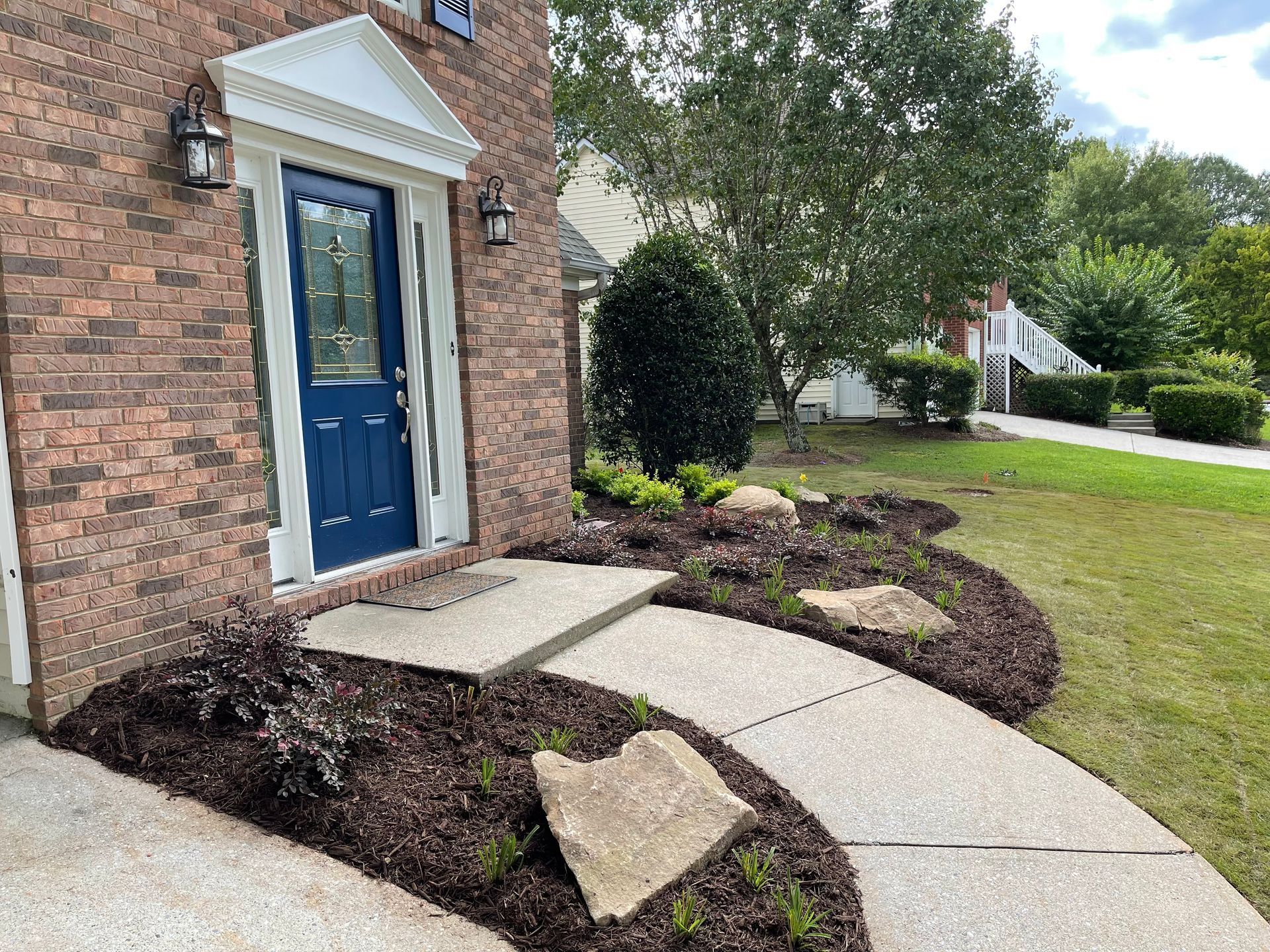 A brick house with a blue door and a walkway leading to it.