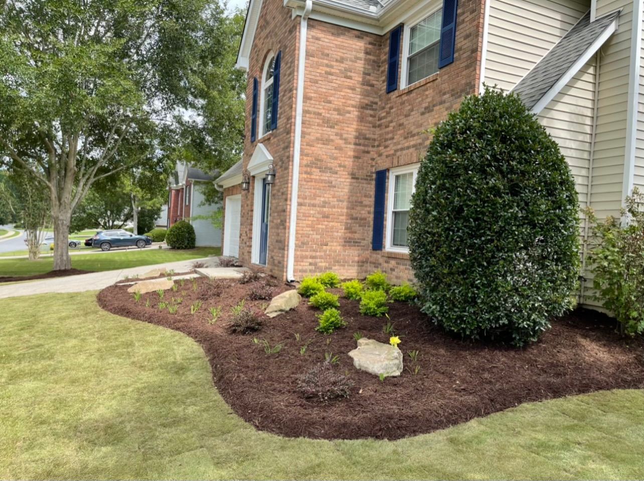 A brick house with a lush green lawn in front of it.