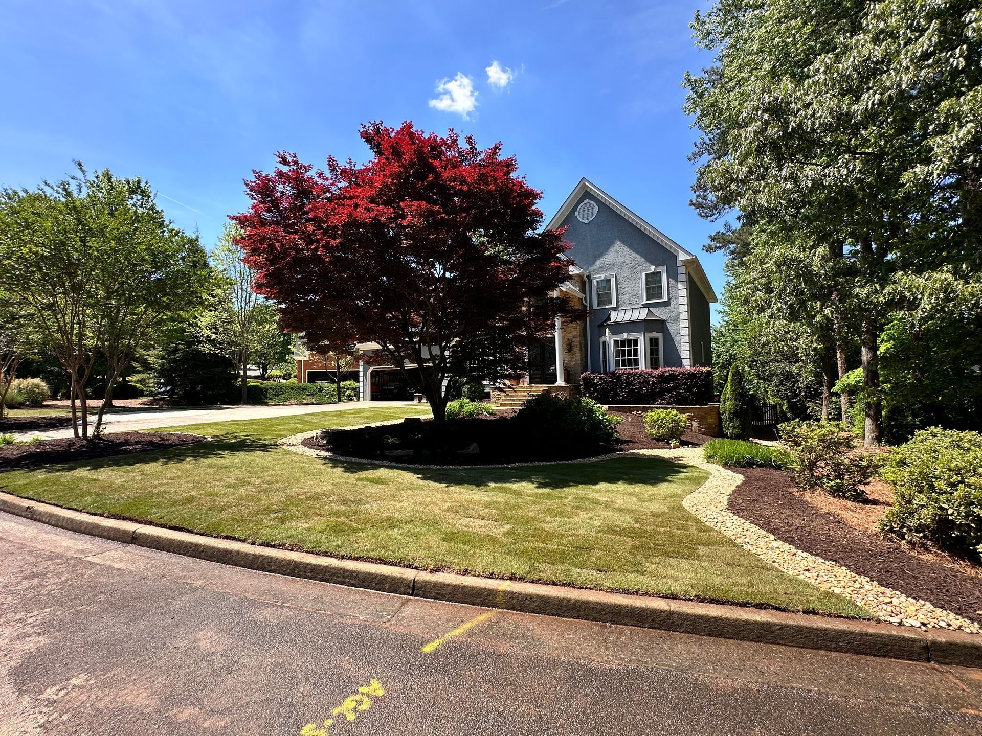 A large house with a lush green lawn and trees in front of it.
