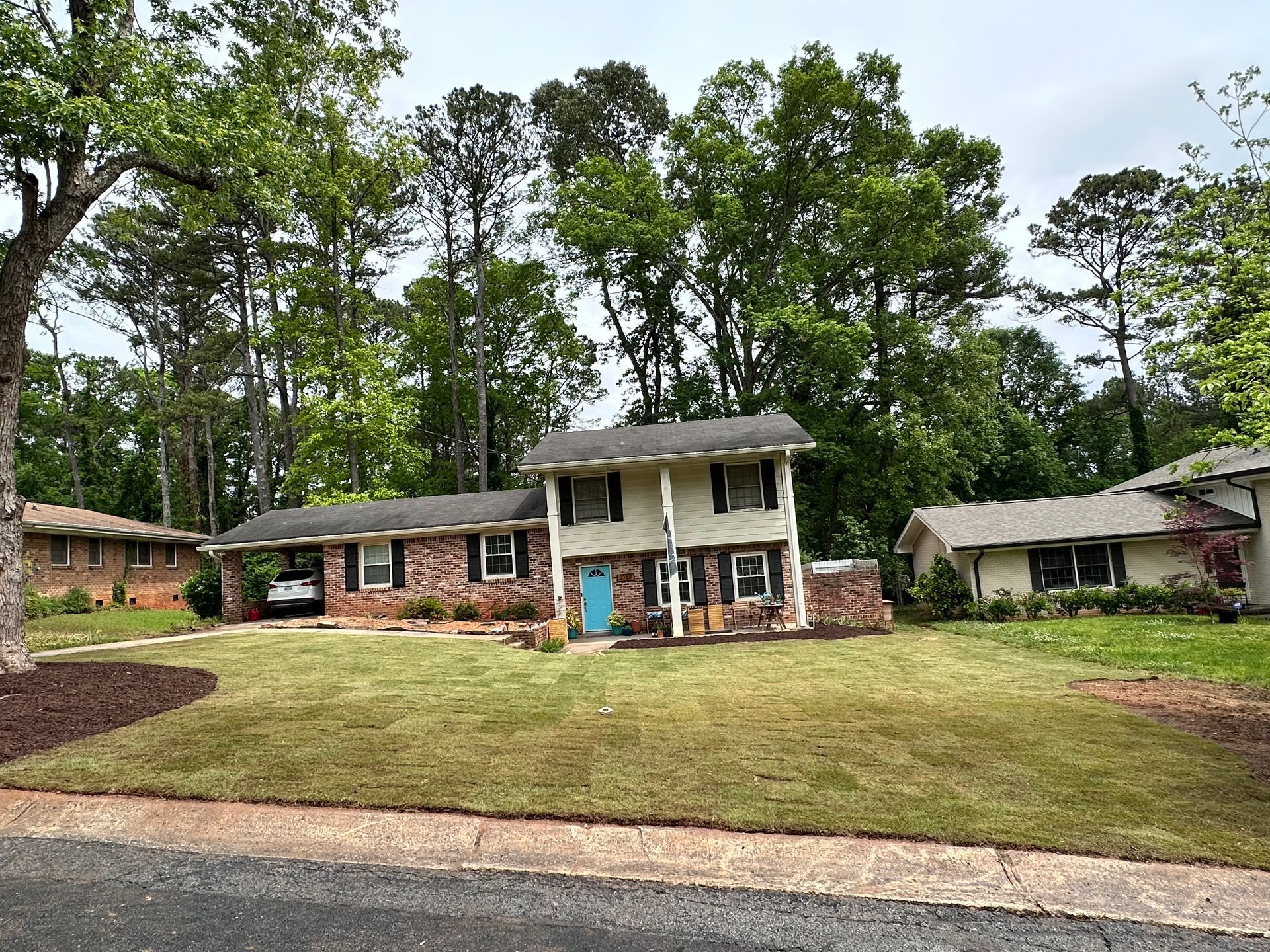 A house with a blue door is surrounded by trees and grass.