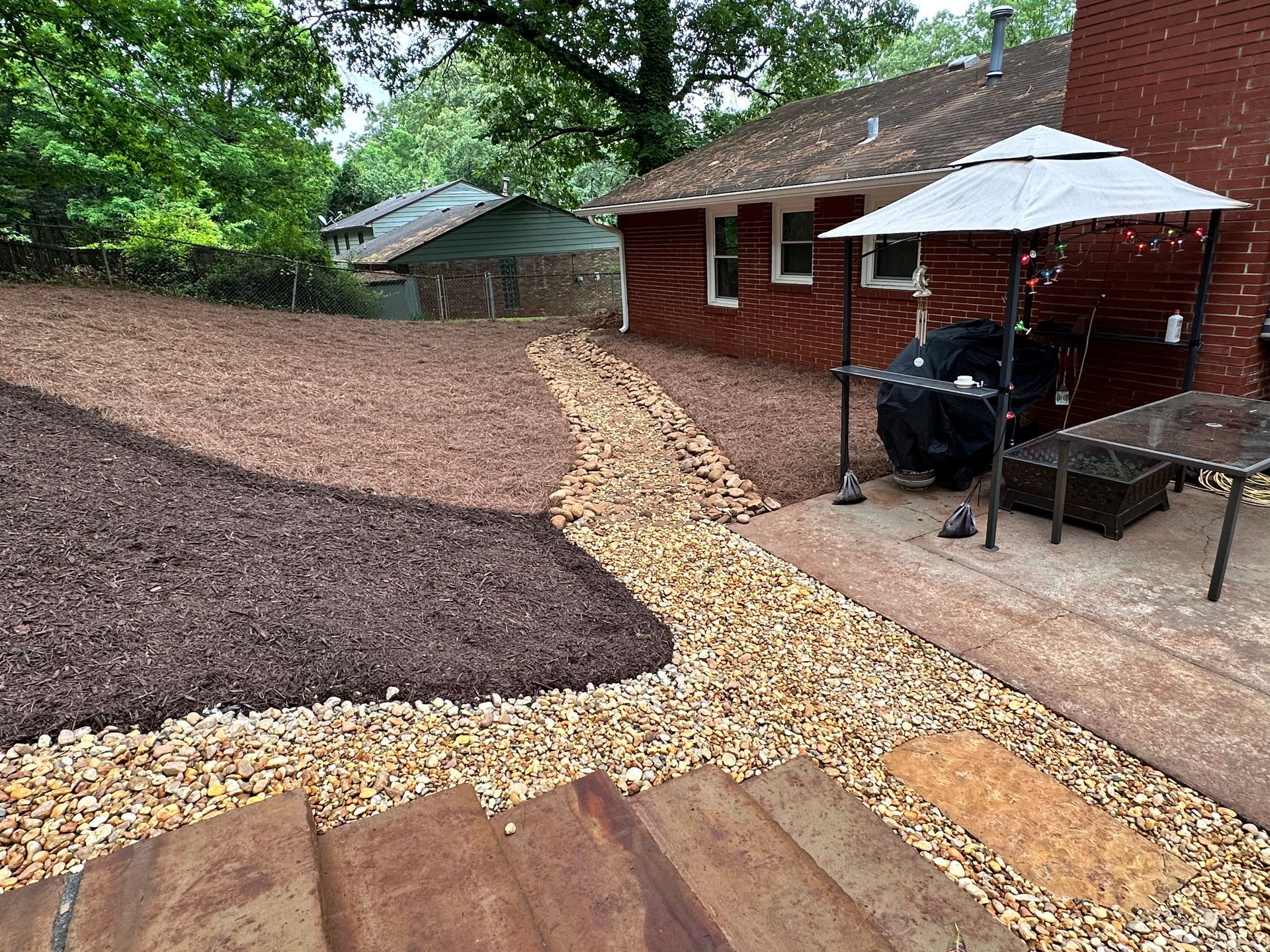 A brick house with a patio and umbrella in the backyard.