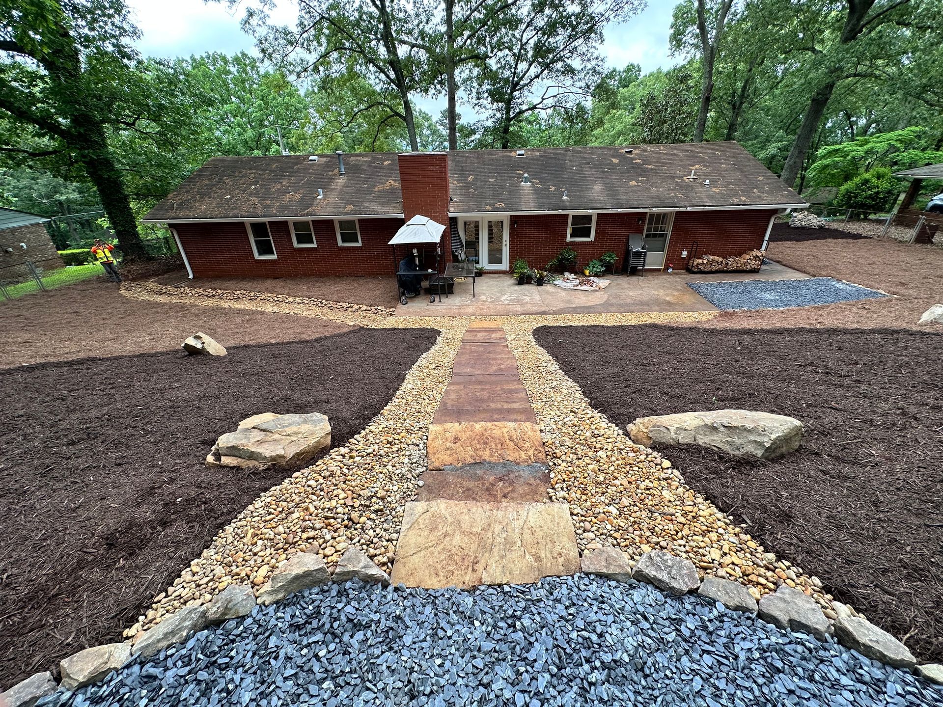 A house with a walkway leading to it surrounded by rocks and mulch.