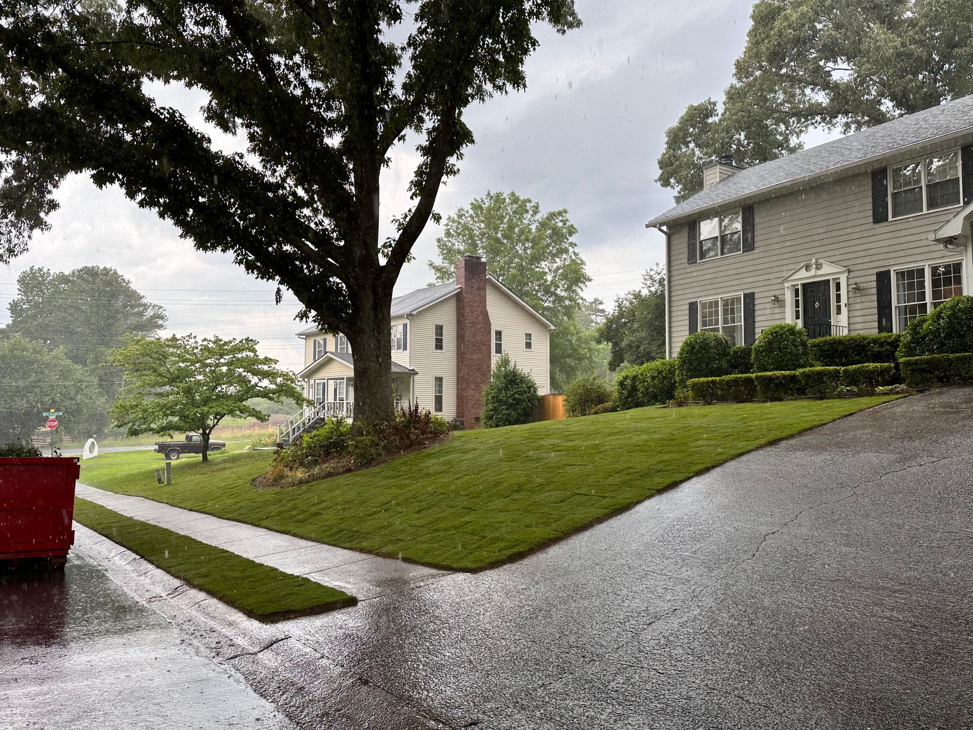 A red truck is parked in front of a house on a rainy day.