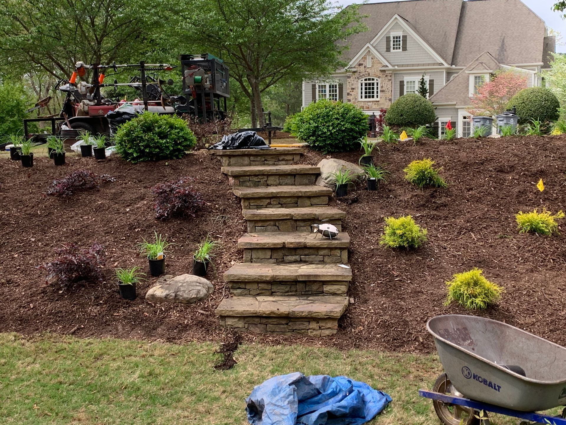 A wheelbarrow is sitting in the grass in front of a house.