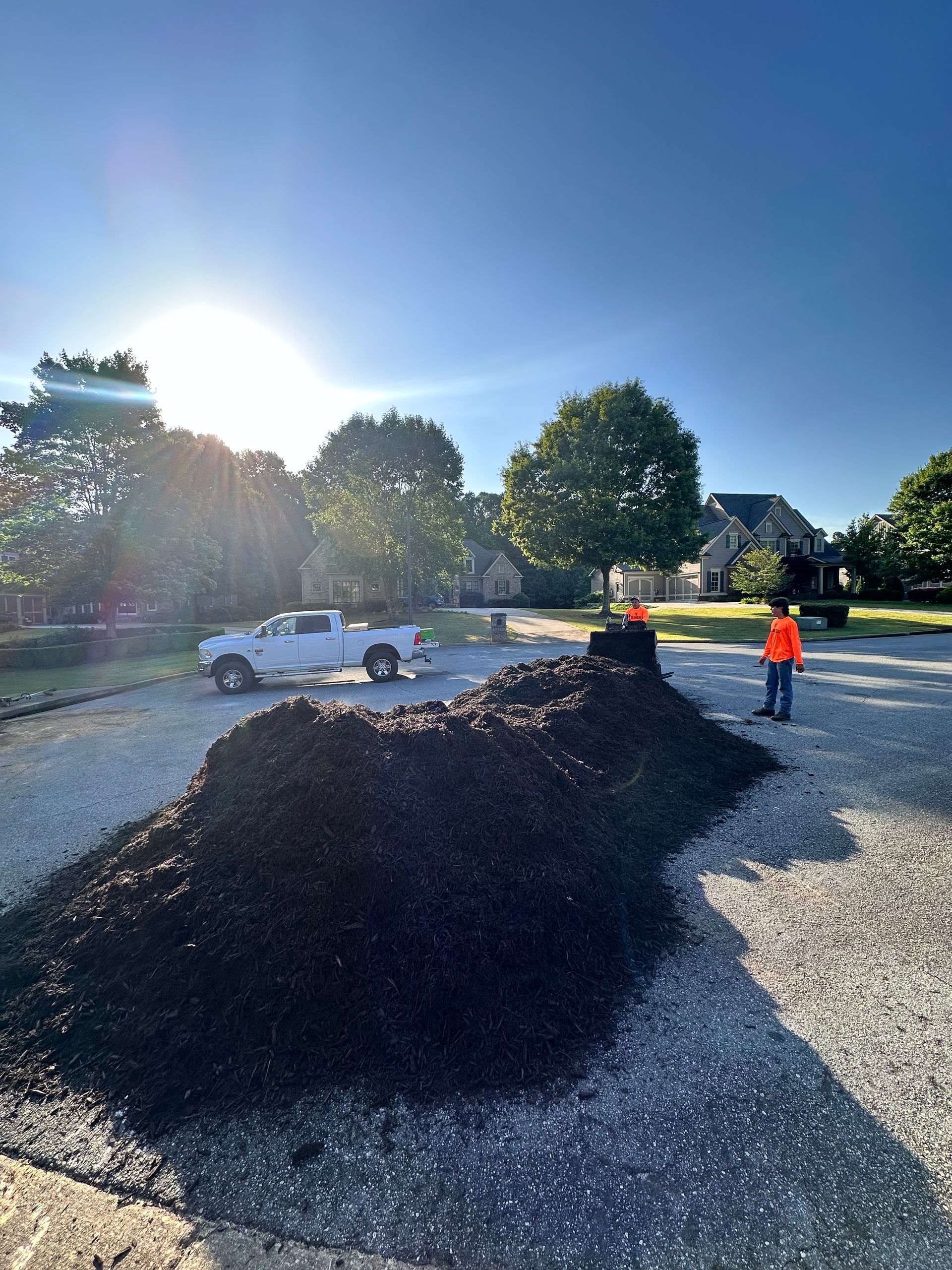 A white truck is parked next to a pile of dirt.
