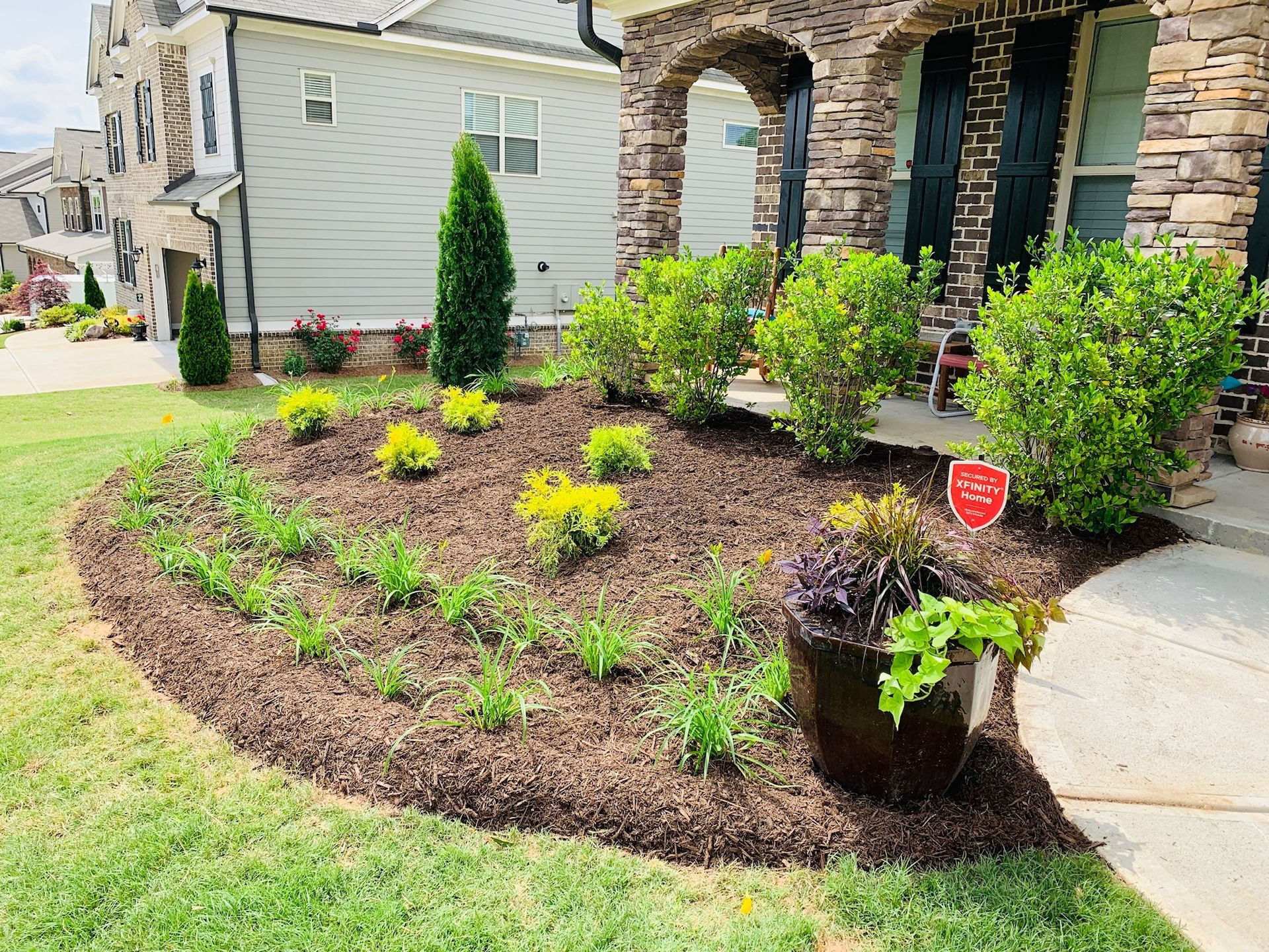 A house with a lush green lawn and a garden in front of it.
