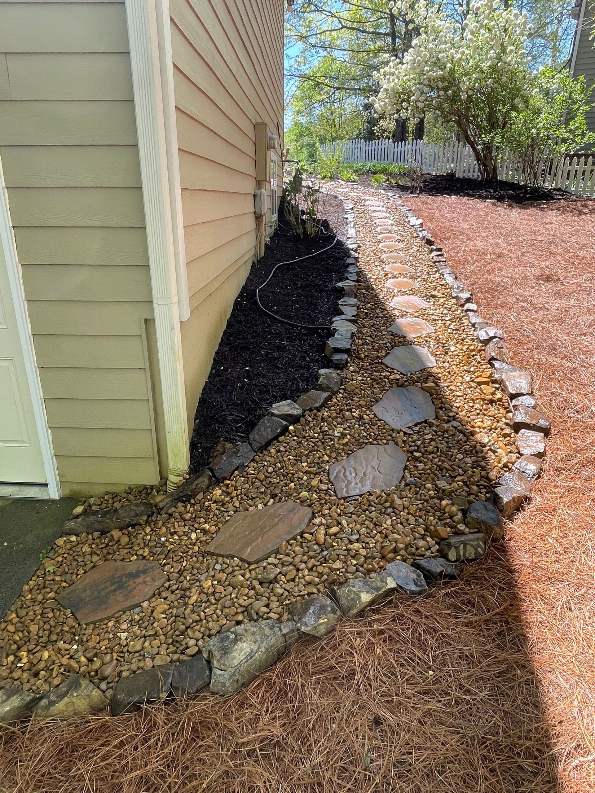 A stone walkway leading to the side of a house.