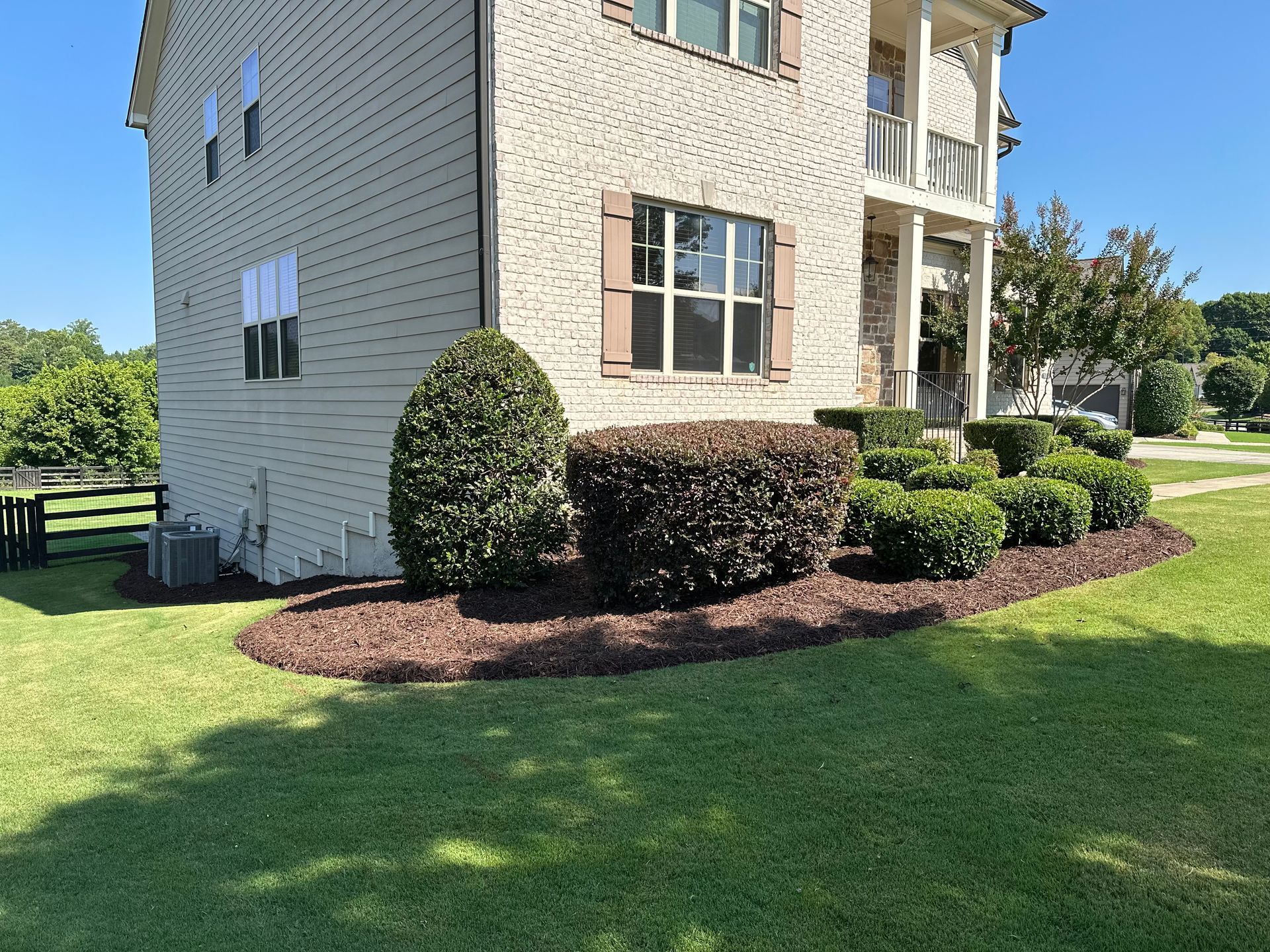 A large white brick house with a lush green lawn in front of it.