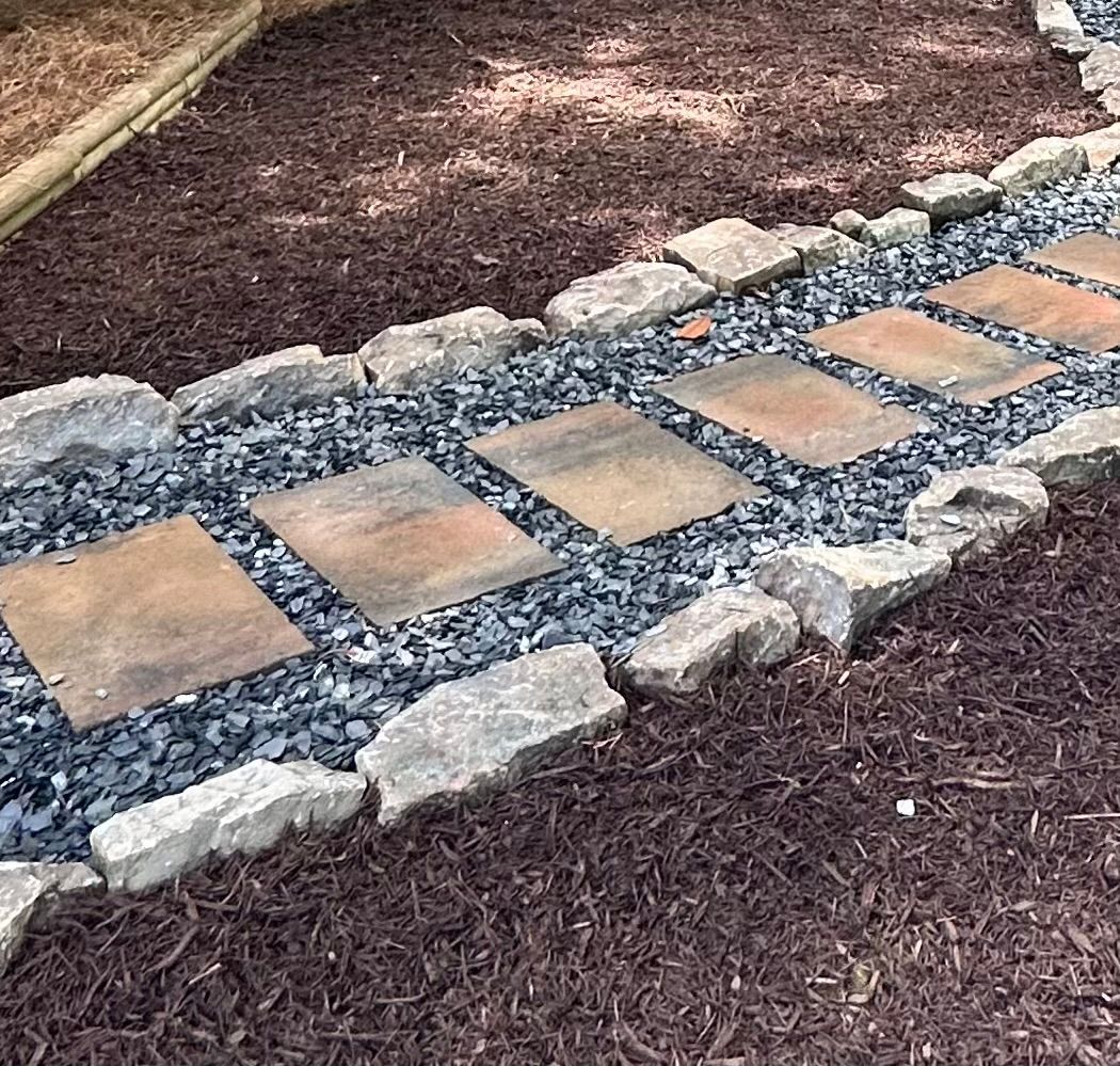 A stone walkway surrounded by rocks and gravel in a yard.