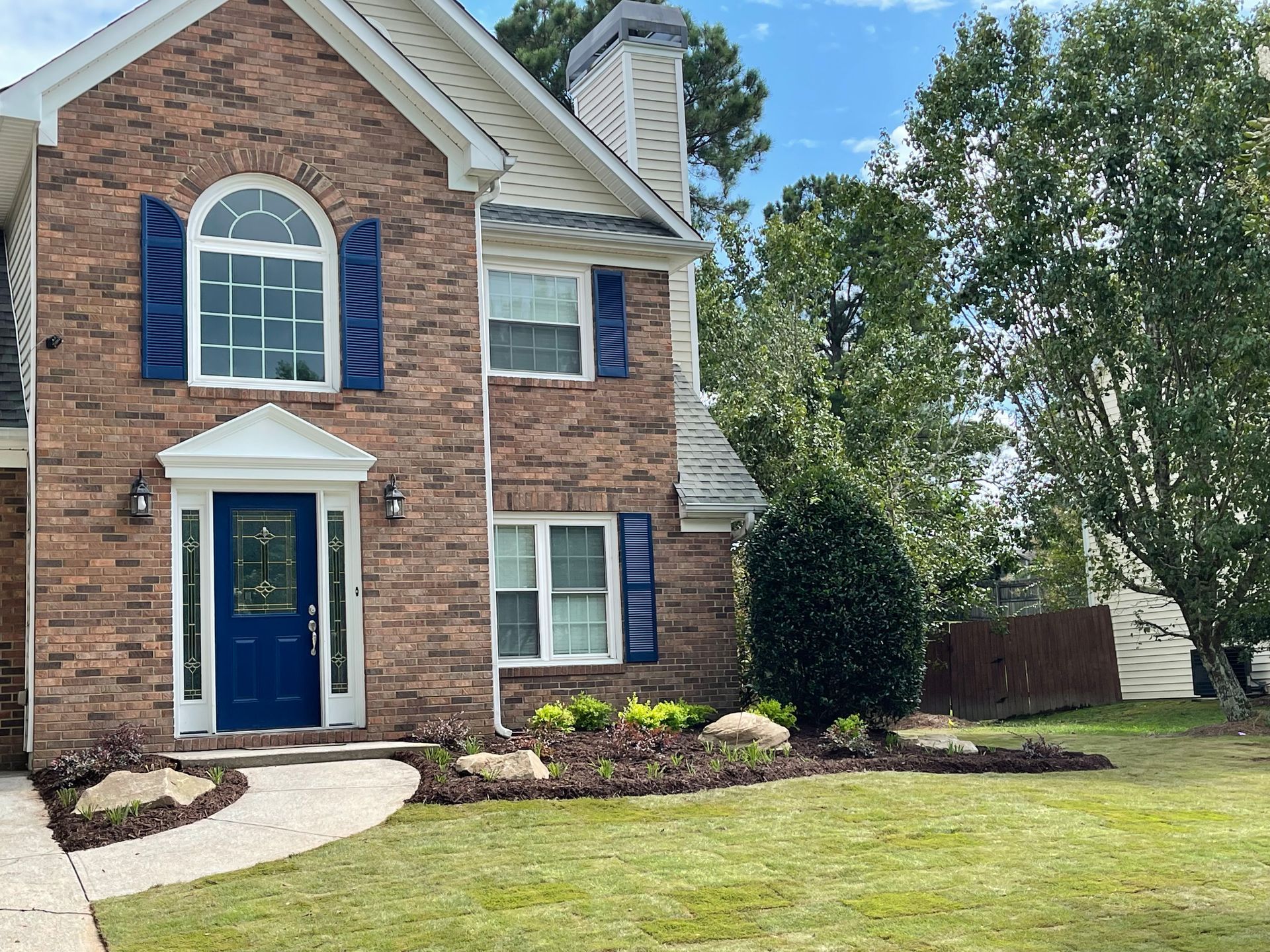 A brick house with blue shutters and a blue door