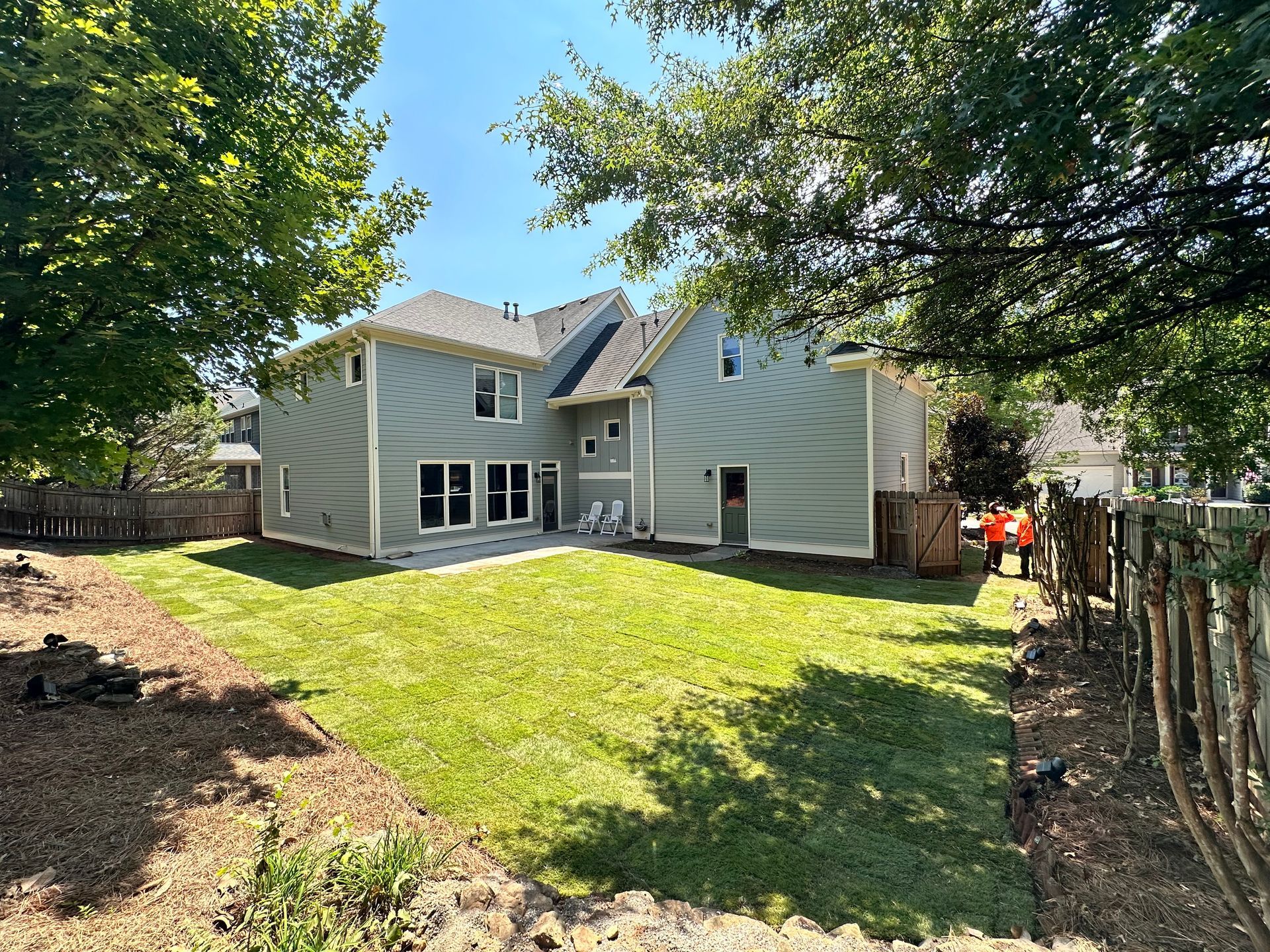 The backyard of a house with a large lawn and a fence.