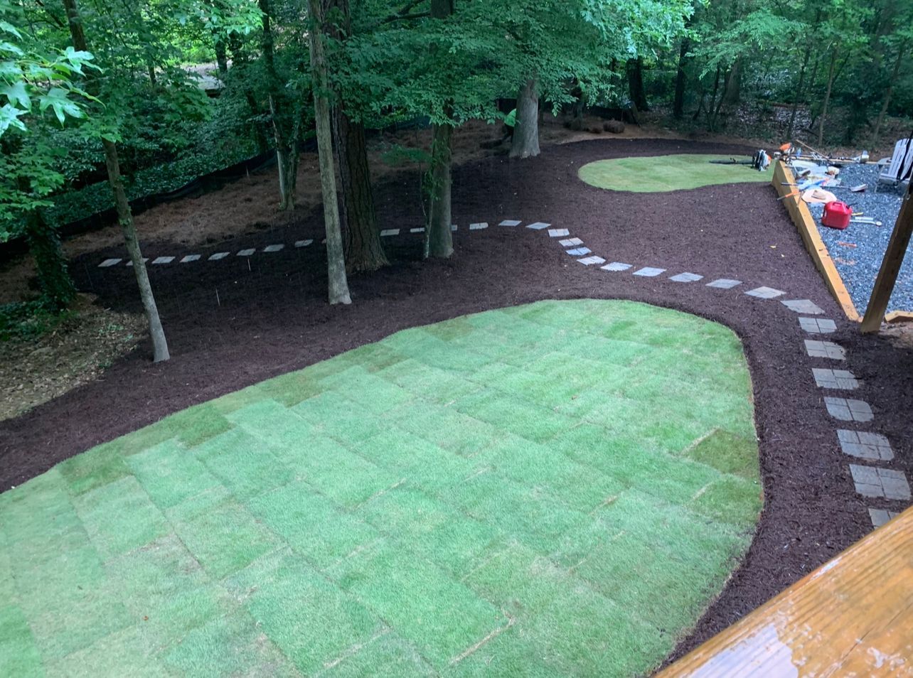 Two men are working on a lawn in front of a house.