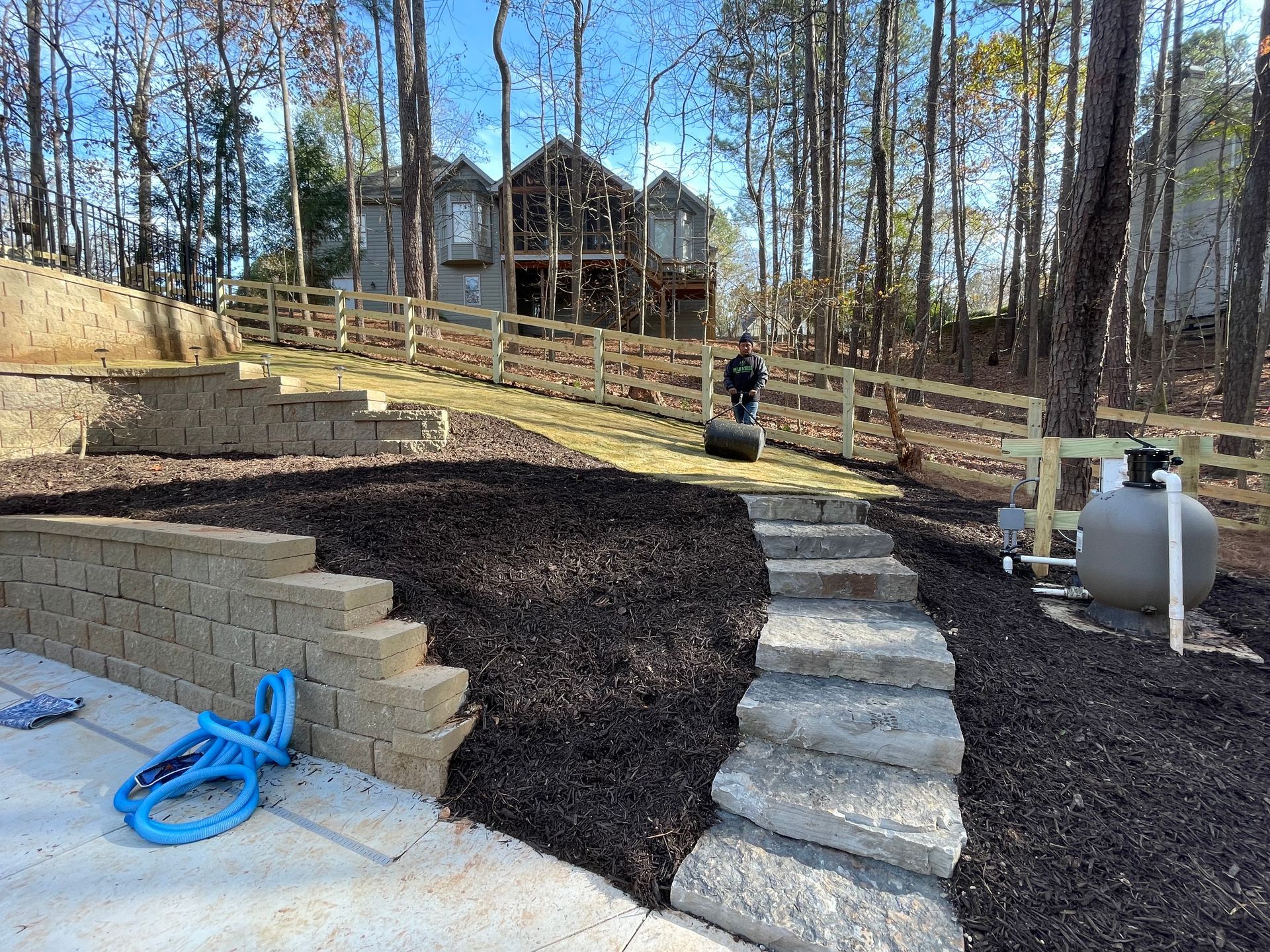 A hose is sitting next to a propane tank in a backyard.
