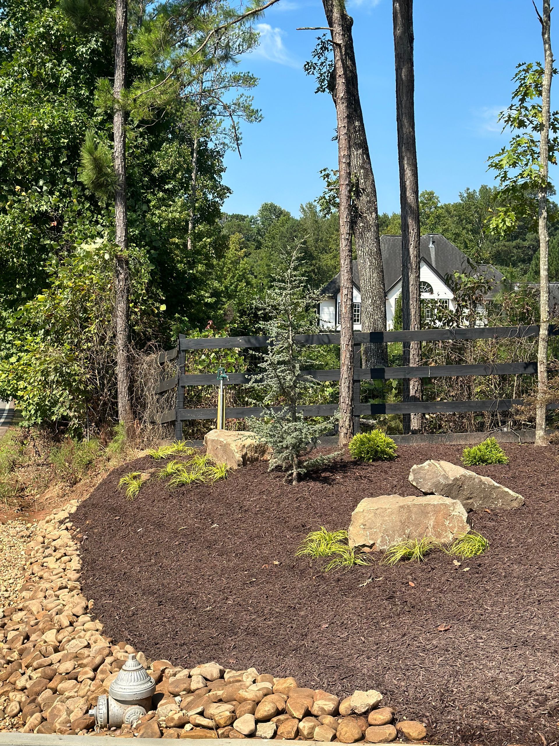 A fire hydrant is in the middle of a garden surrounded by trees.