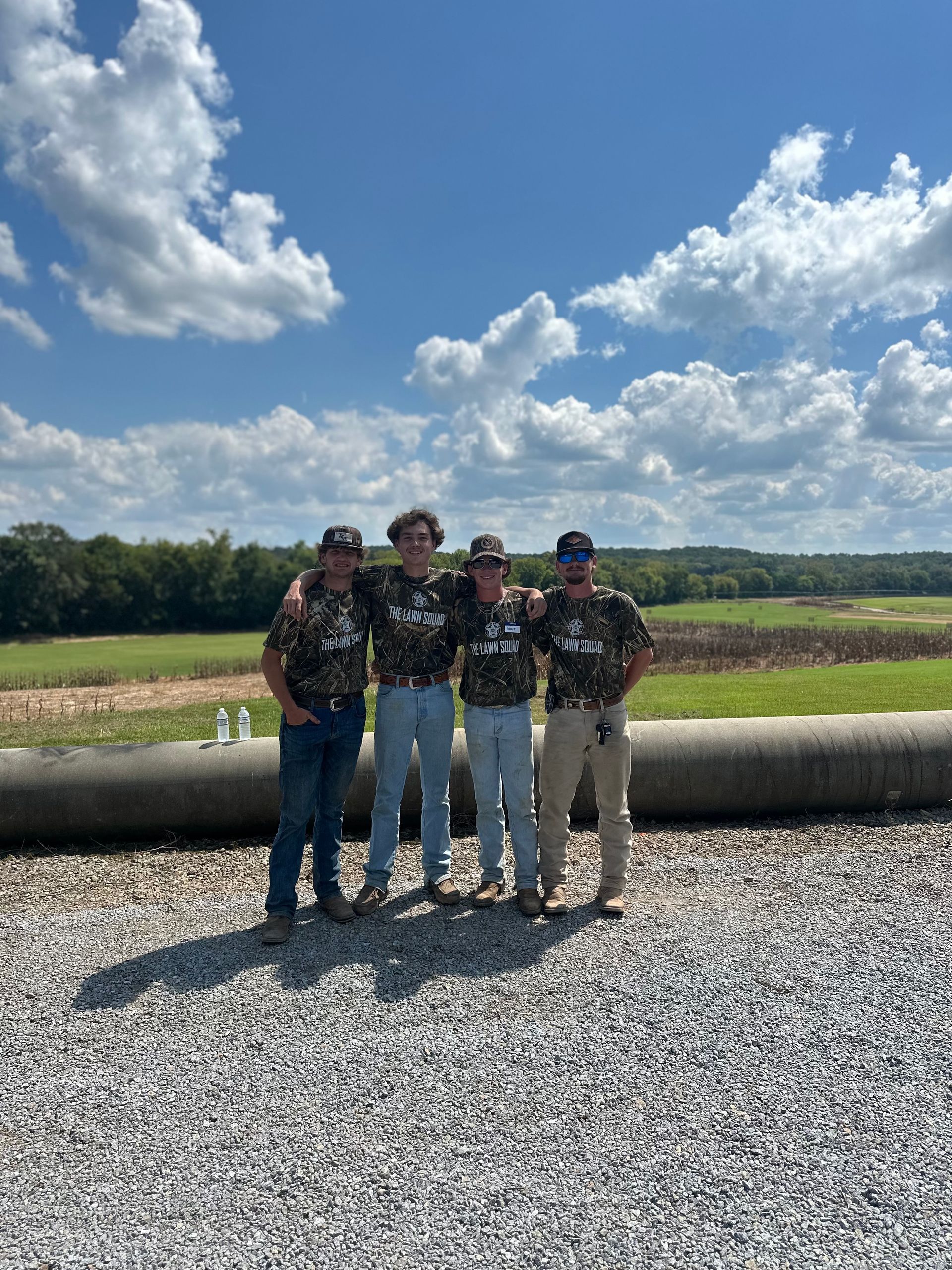 A group of men are standing next to each other in front of a large pipe.
