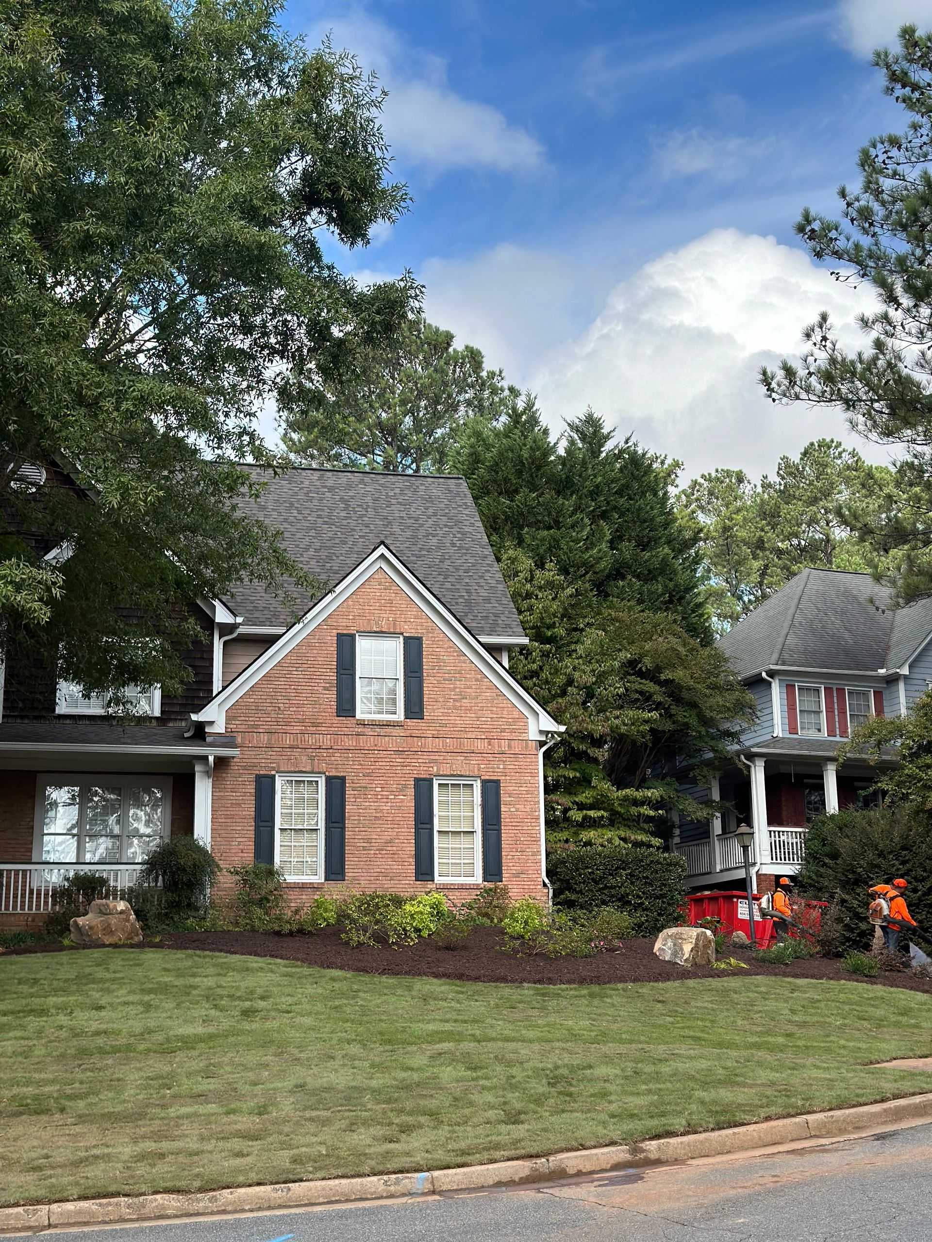 A brick house with black shutters in a residential neighborhood