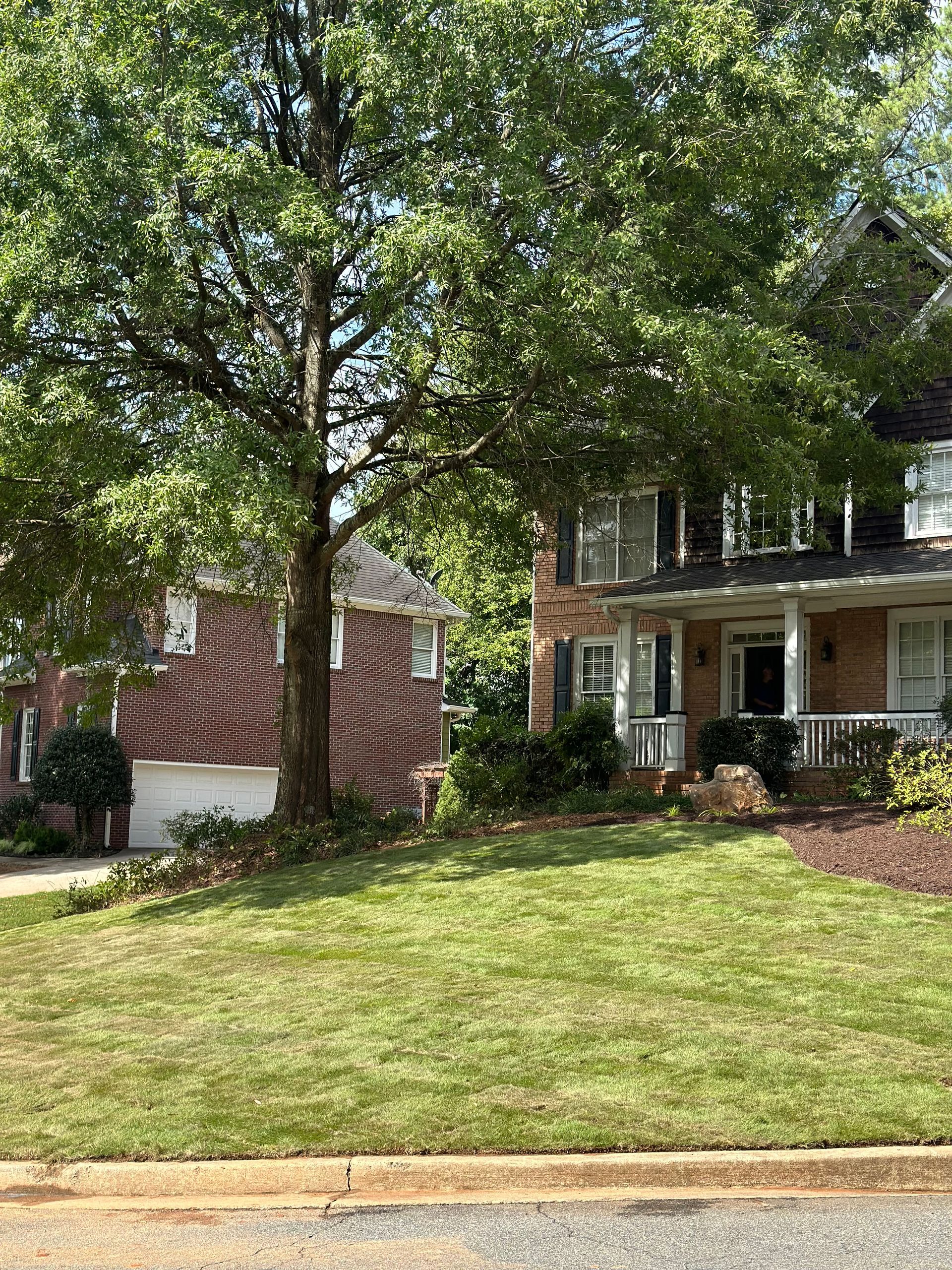 A brick house with a large lawn in front of it.