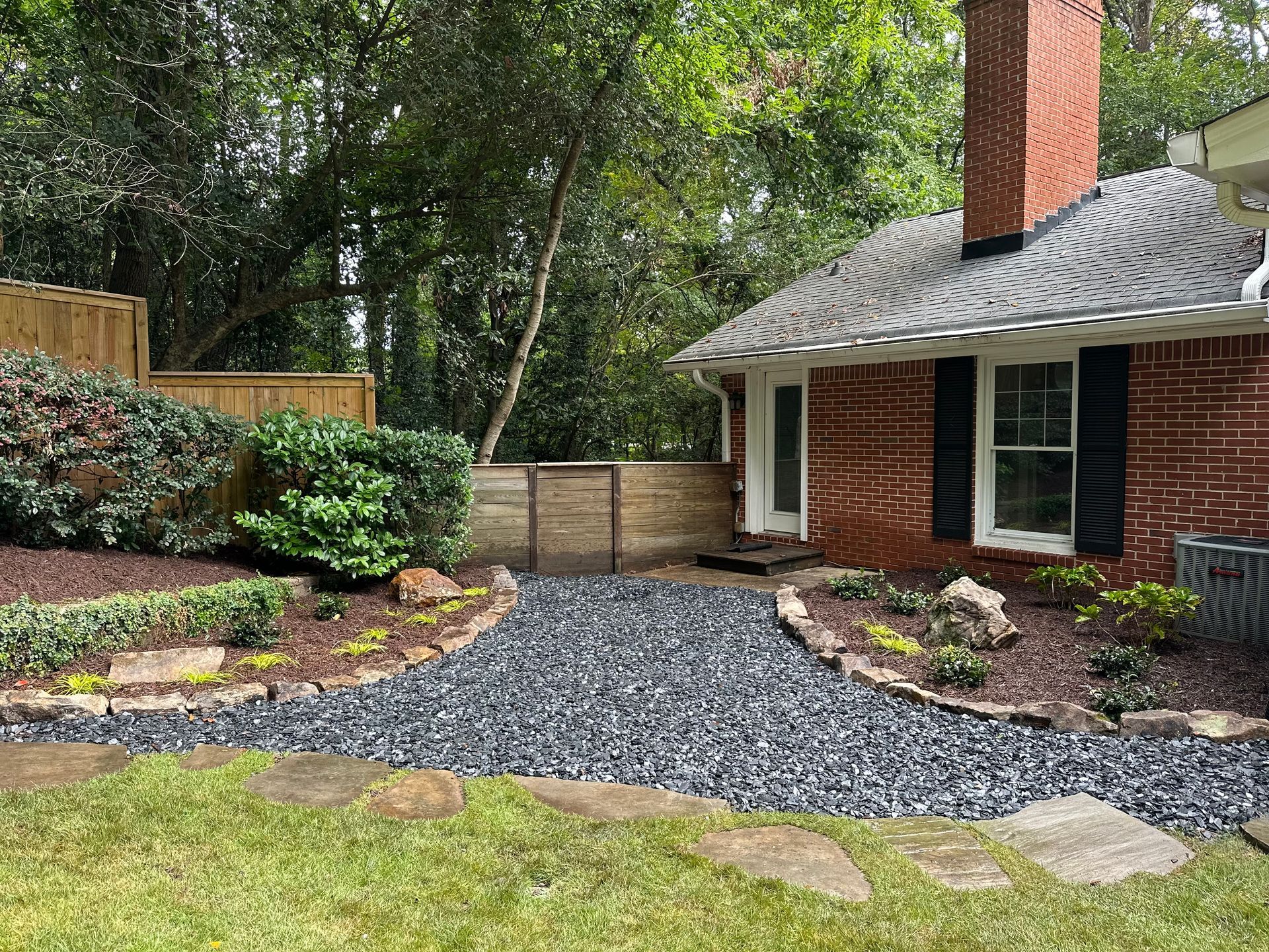 A brick house with a gravel driveway leading to it.