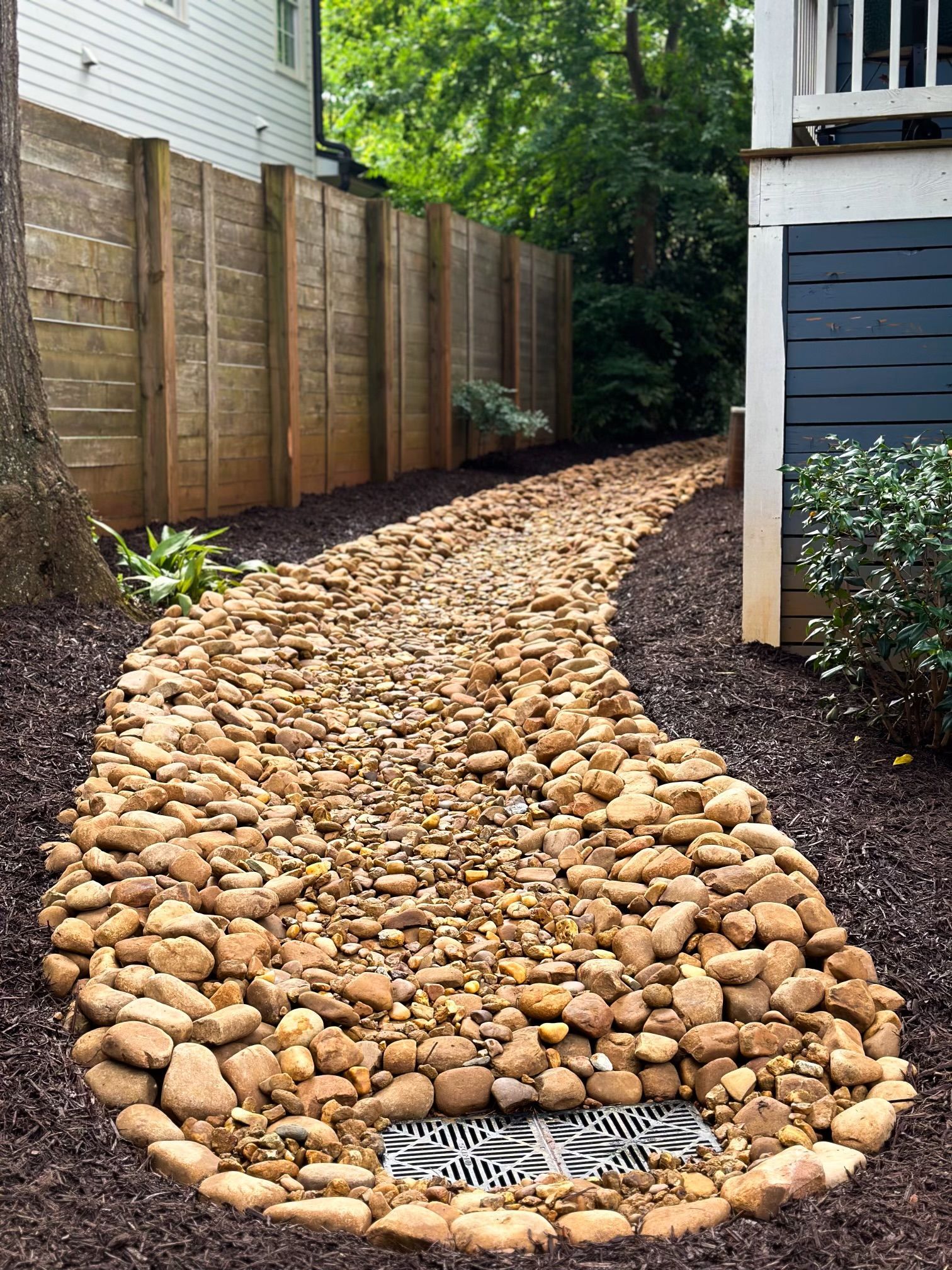 A stone path leading to a house with a wooden fence.